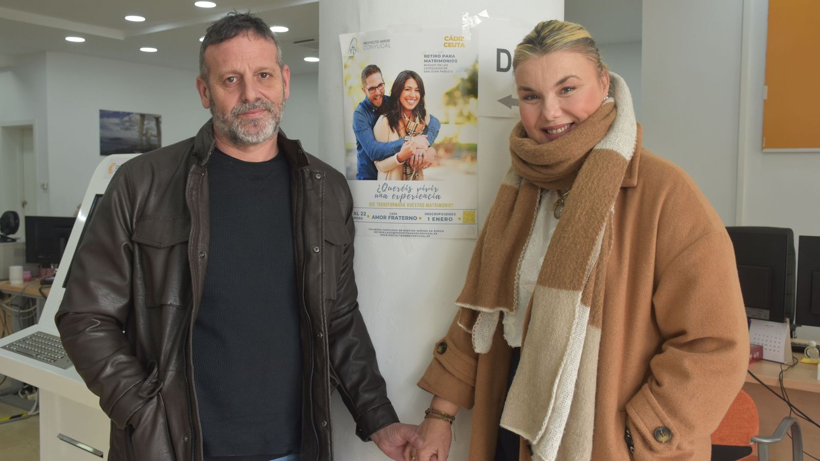 Fran Morales y Eva Blanco posan junto al cartel del retiro espiritual en Ceuta, previsto para este fin de semana y aplazado para abril
