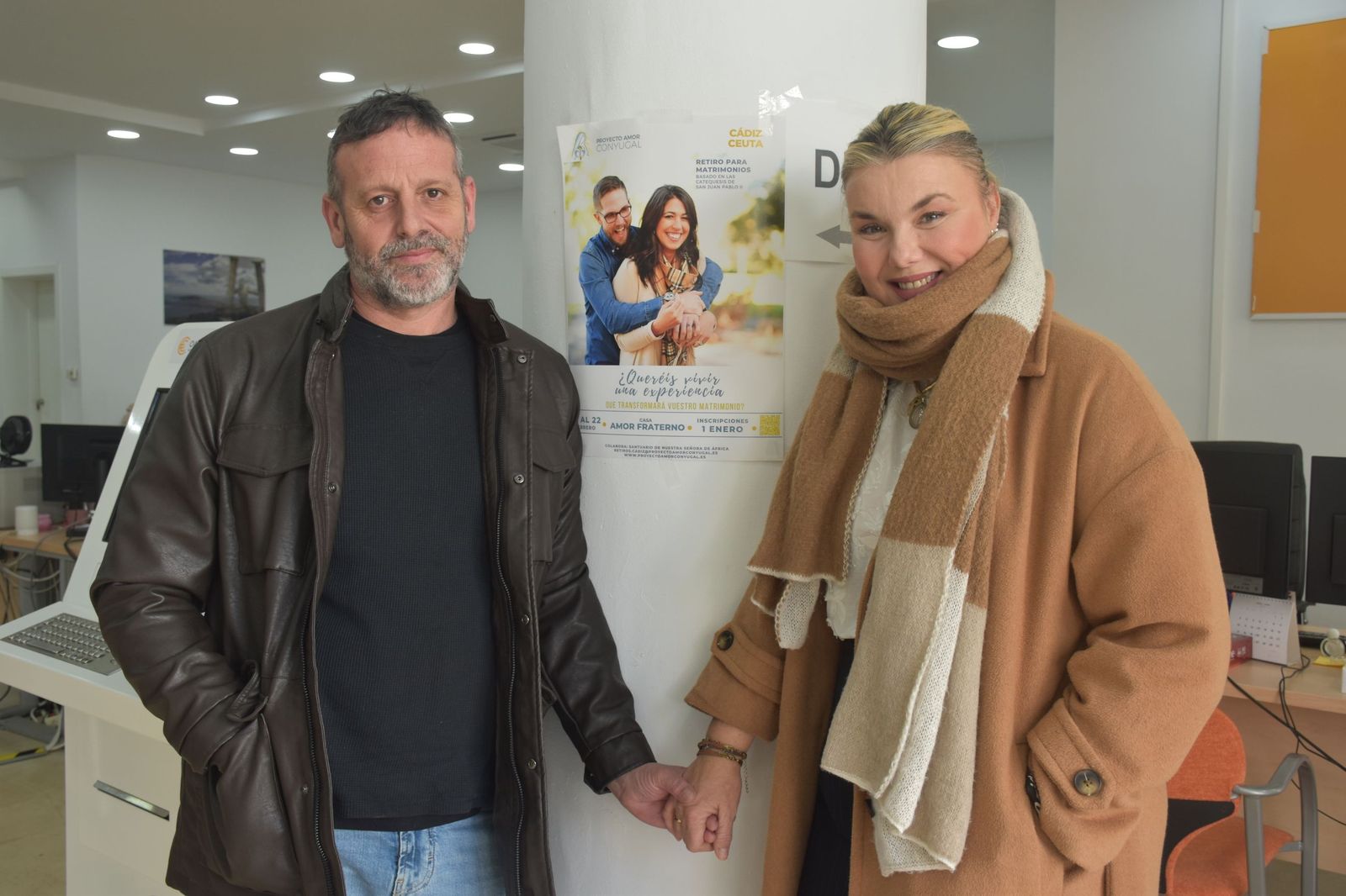Fran Morales y Eva Blanco posan junto al cartel del retiro espiritual en Ceuta, previsto para este fin de semana y aplazado para abril