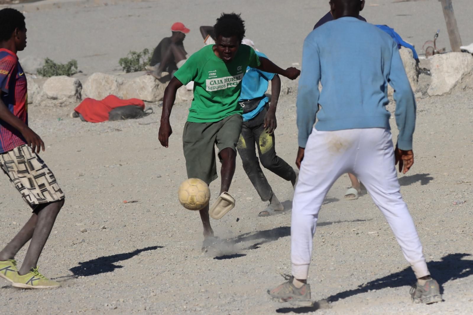 Migrantes jugando al fútbol en la playa a la espera de resolver su futuro
