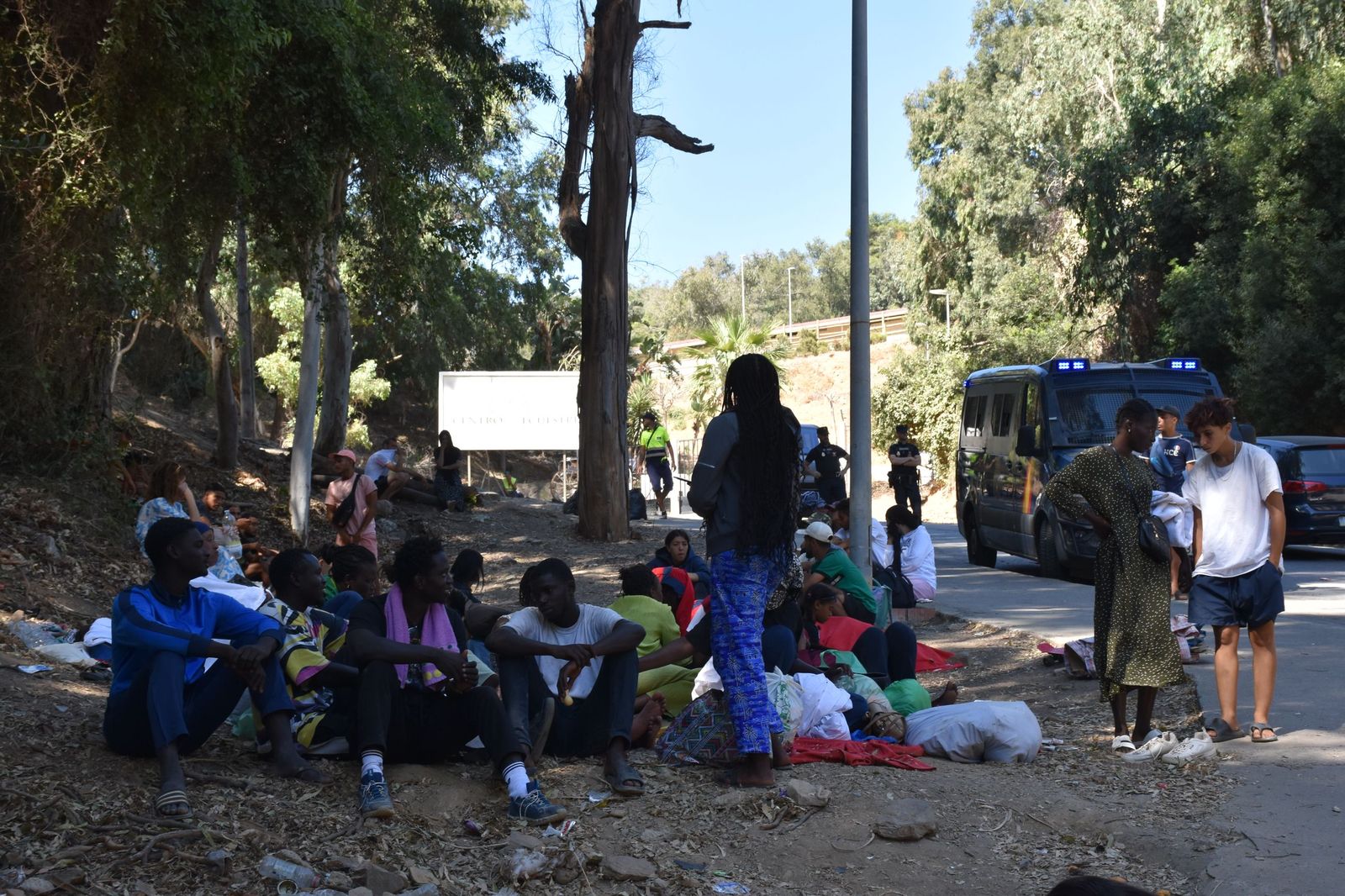 Personas migrantes sentadas en la cuneta de la carretera que conduce al CETI este miércoles