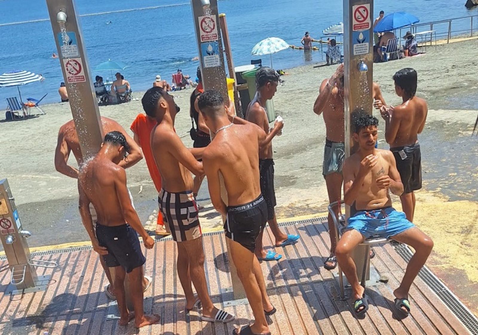 Migrantes haciendo uso de las duchas de la playa del Chorrillo