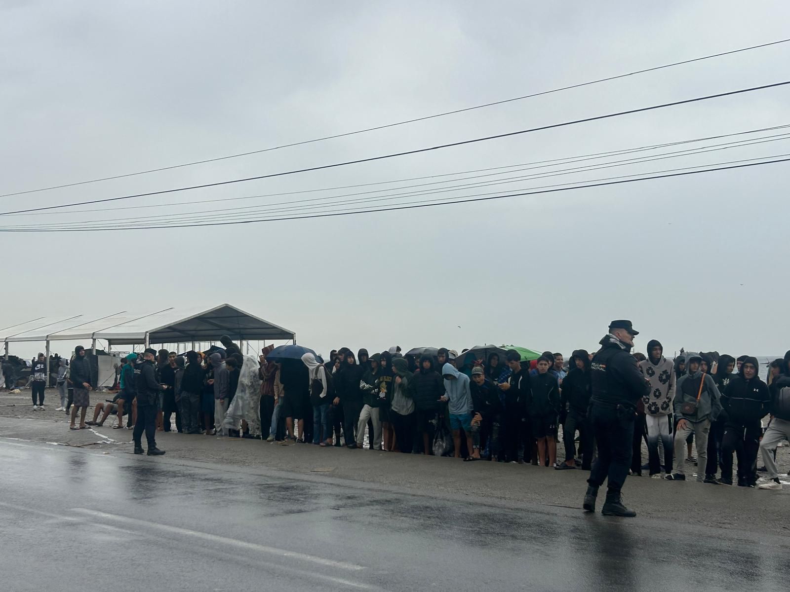 Un grupo de menores migrantes, en fila con la intención de que los trasladen a centros de acogida
