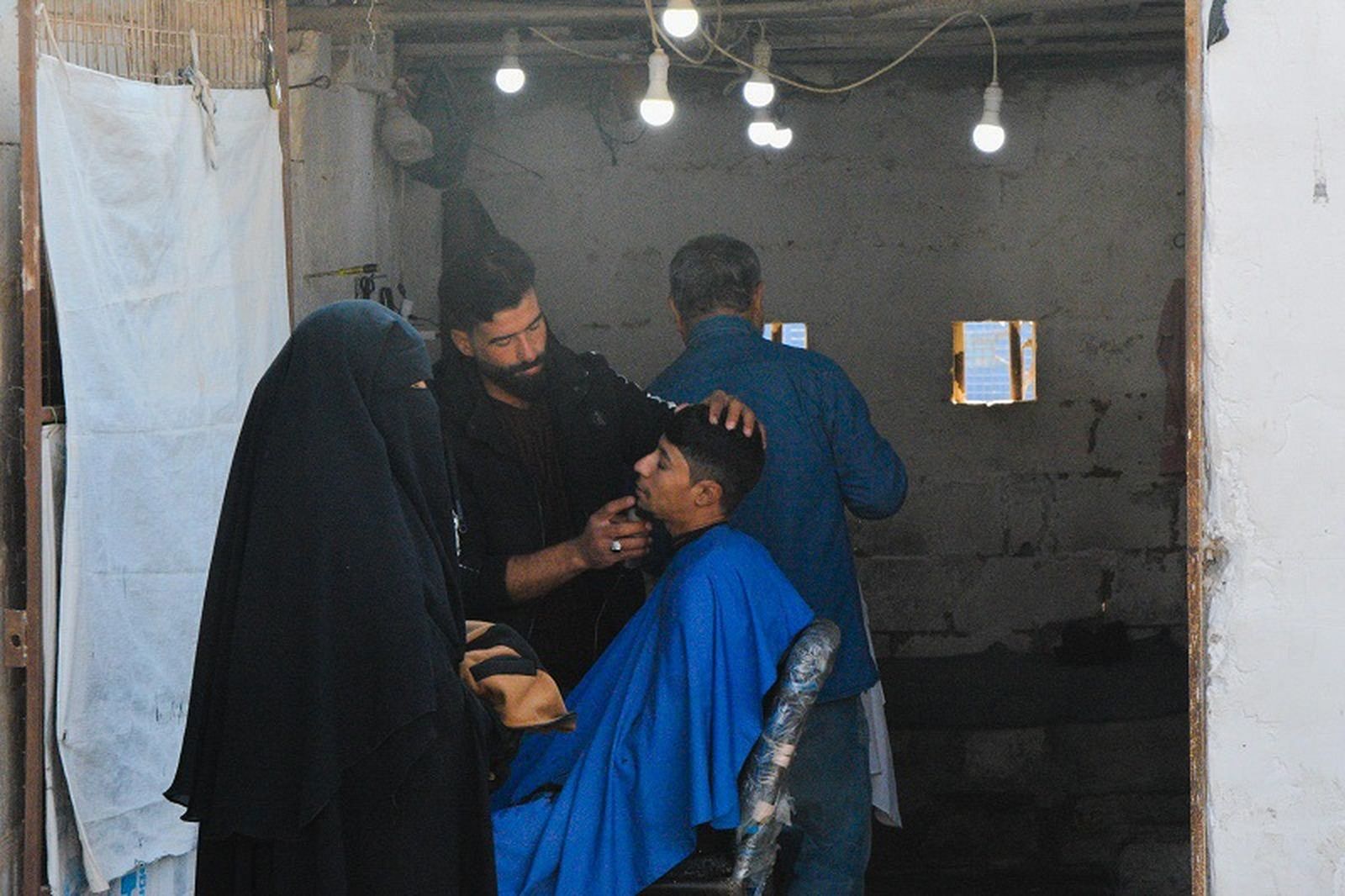 Una mujer que viste niqab junto a una peluquería improvisada en el campamento de Al Hol, en Siria, en diciembre de 2022. / FOTO J.I.MOTA