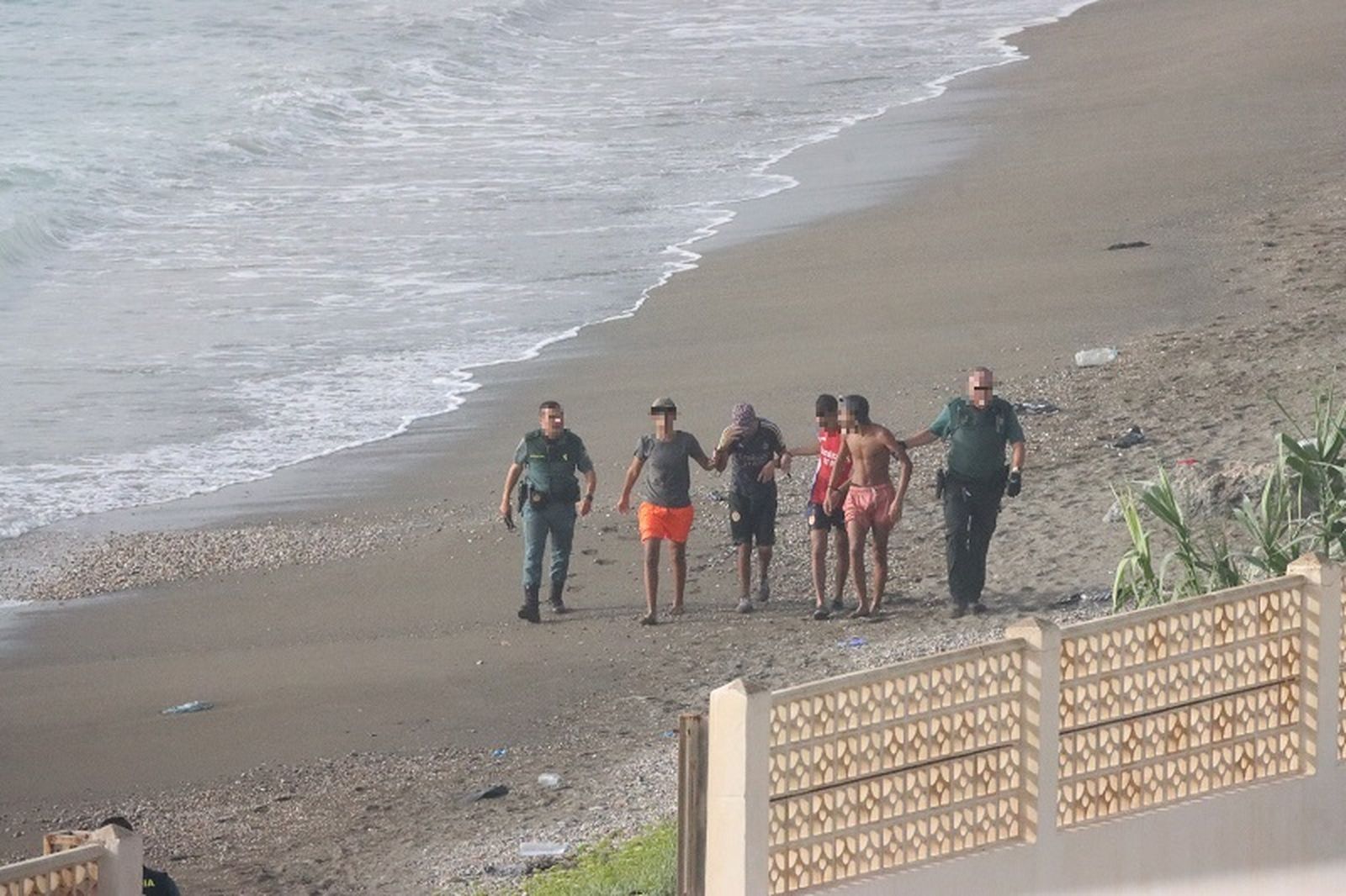 Dos agentes de la Guardia Civil expulsan de la playa del Tarajal a cuatro migrantes recién llegados este martes. / FOTO REDUAN
