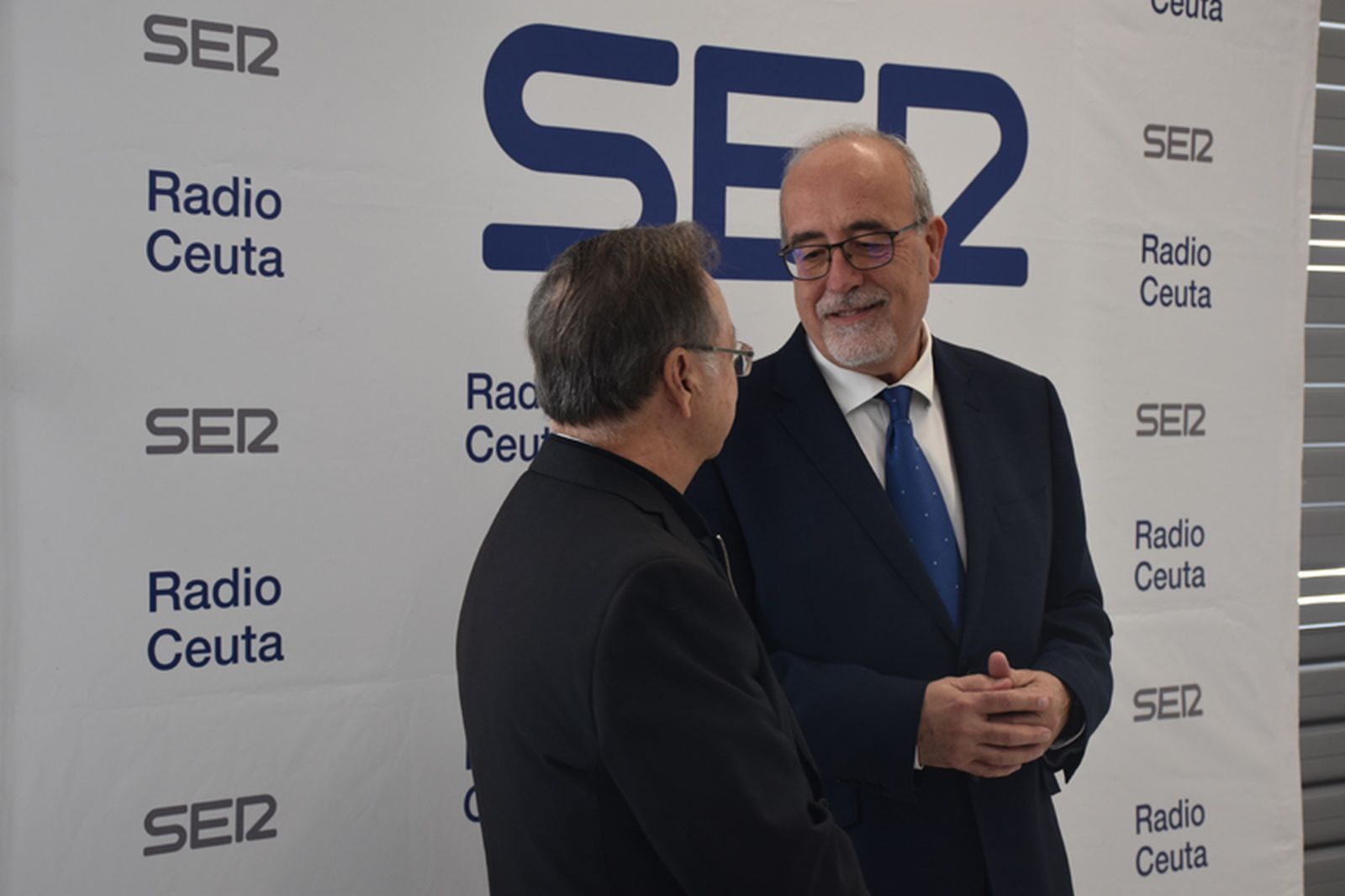El director de Radio Ceuta, Joaquín Guirval, conversa con el presidente de Ceuta, Juan Vivas, junto al photocall dispuesto en la Estación del Ferrocarril. / FOTO G.S.