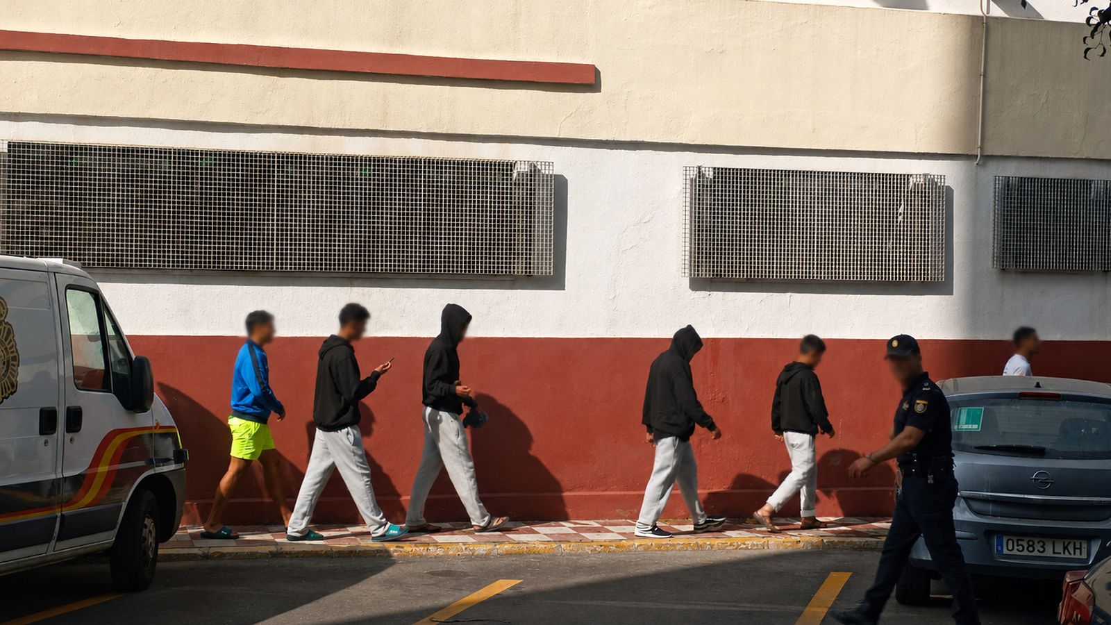 Un policía acompaña a varios jóvenes al aparcamiento de la Jefatura