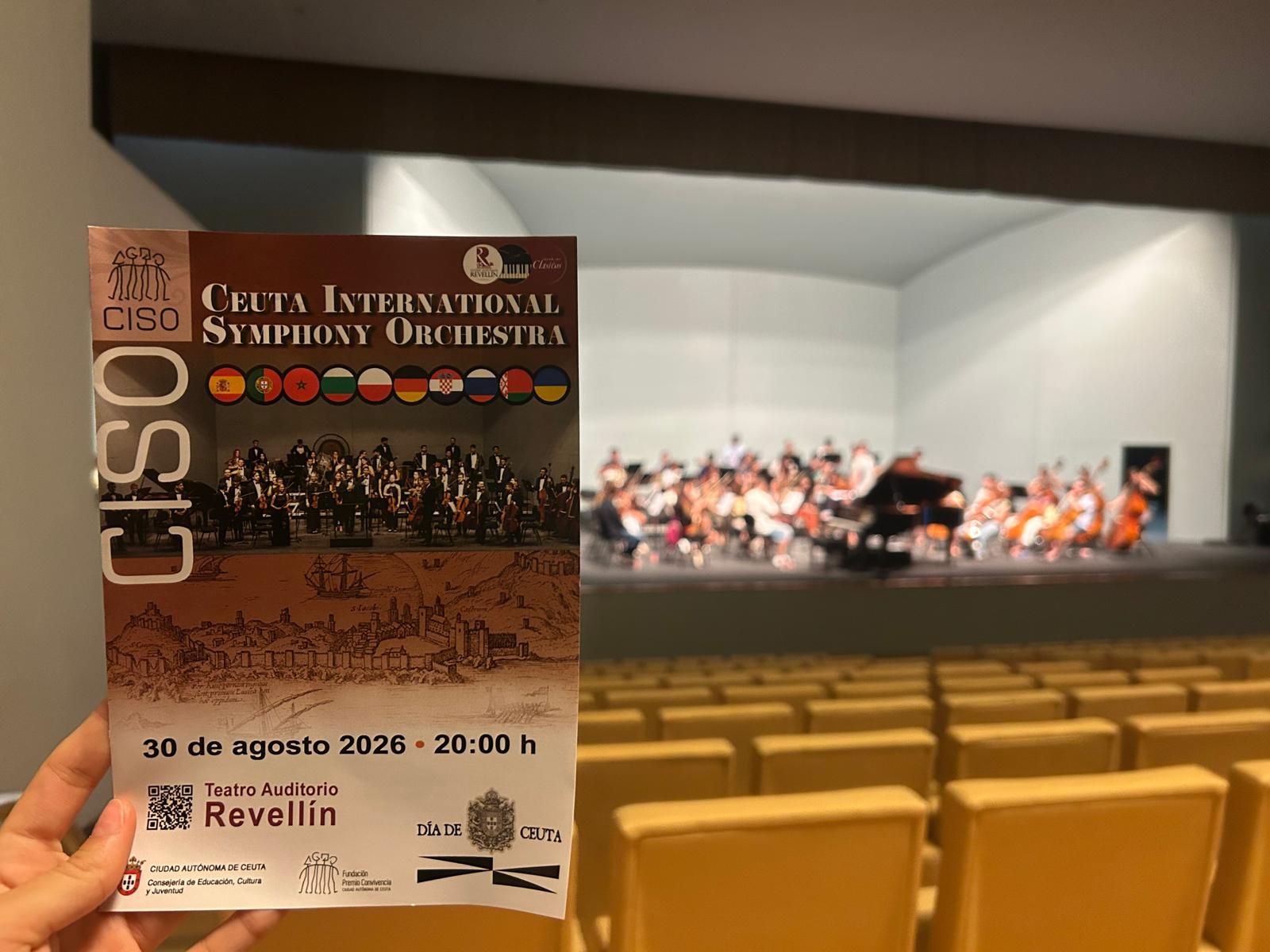 Programa del concierto de la CISO y, de fondo, la orquesta en el ensayo general previo al espectáculo
