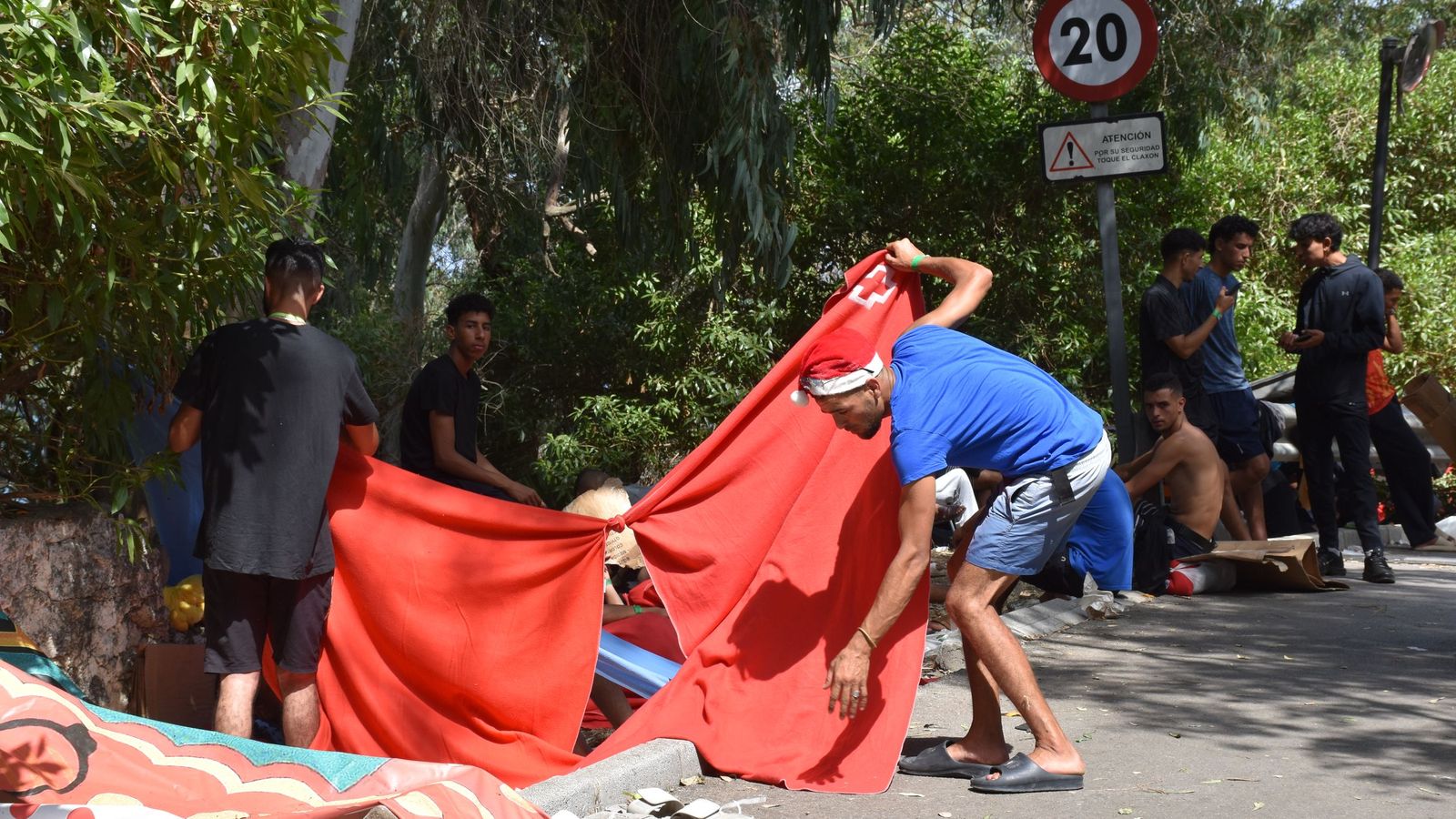 Migrantes en las inmediaciones del CETI a la espera de ingresar en las instalaciones, este jueves