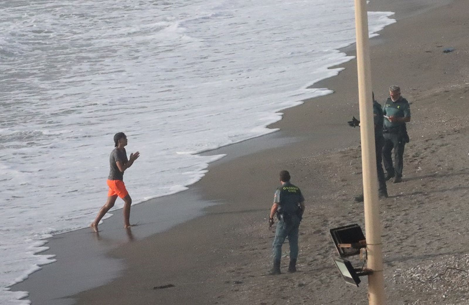 Un migrante que acababa de entrar a Ceuta caminando hacia tres agentes de la Guardia Civil. / FOTO REDUAN