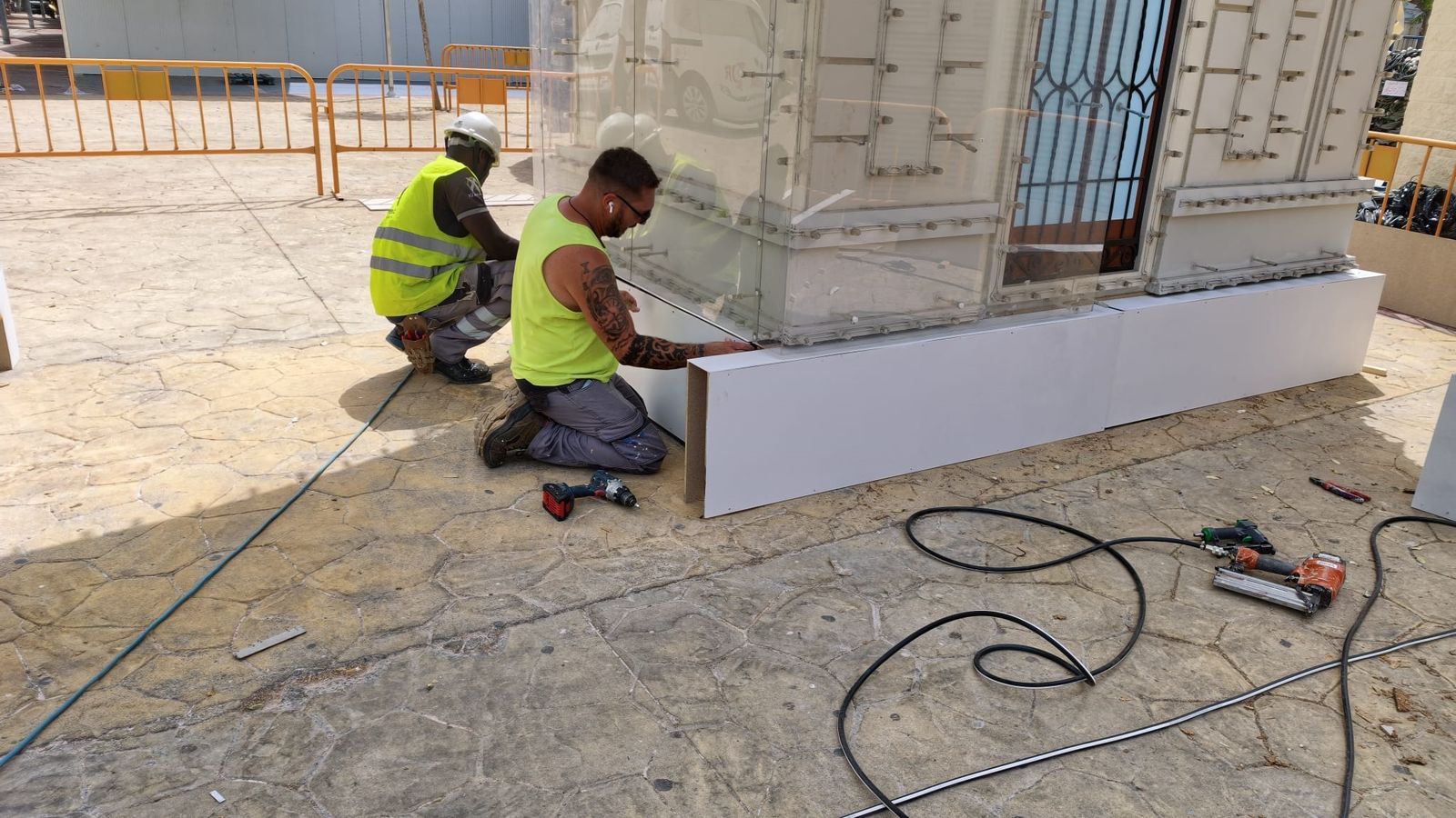 Dos trabajadores retocan la estructura de la portada del ferial