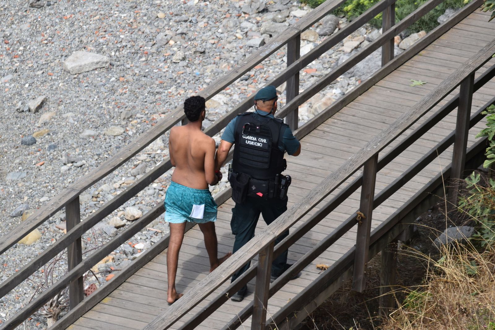 Un agente de la Guardia Civil acompaña a un joven migrante recién localizado tras acceder a Ceuta este lunes