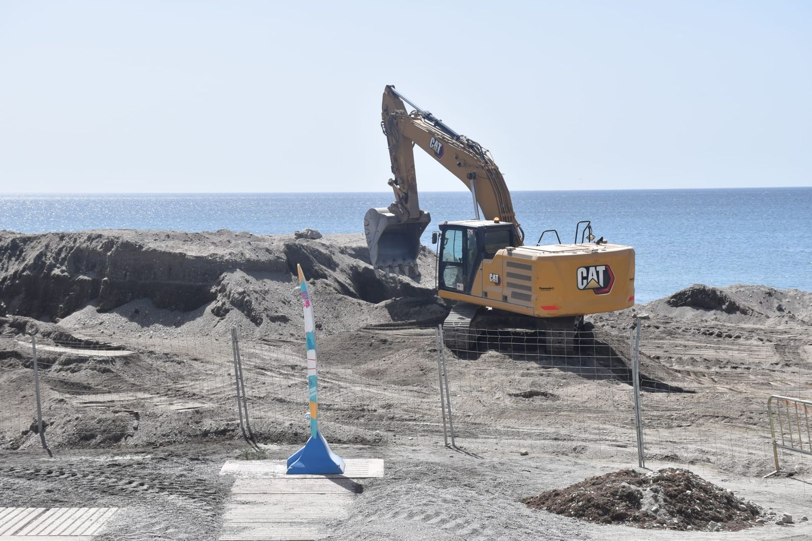 Operarios trabajando en la playa del Tarajal con grandes máquinas