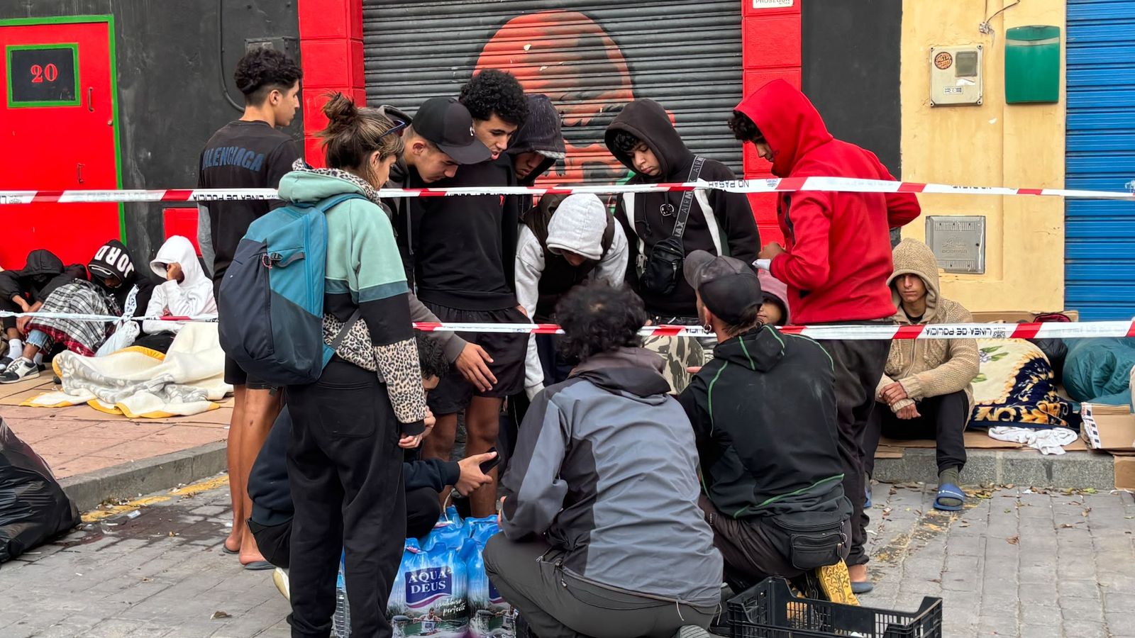 Voluntarios llevan agua y enchufes para cargar móviles al asentamiento de menores en la plaza vieja