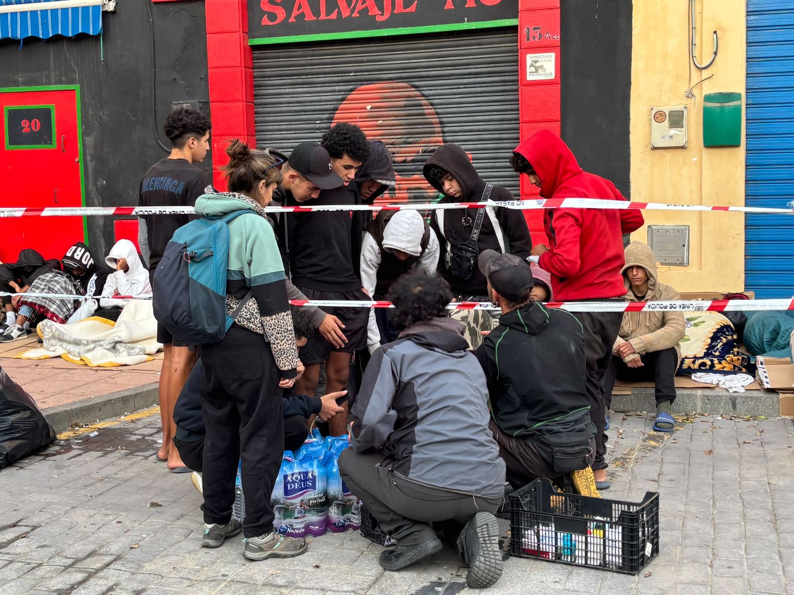 Voluntarios llevan agua y enchufes para cargar móviles al asentamiento de menores en la plaza vieja