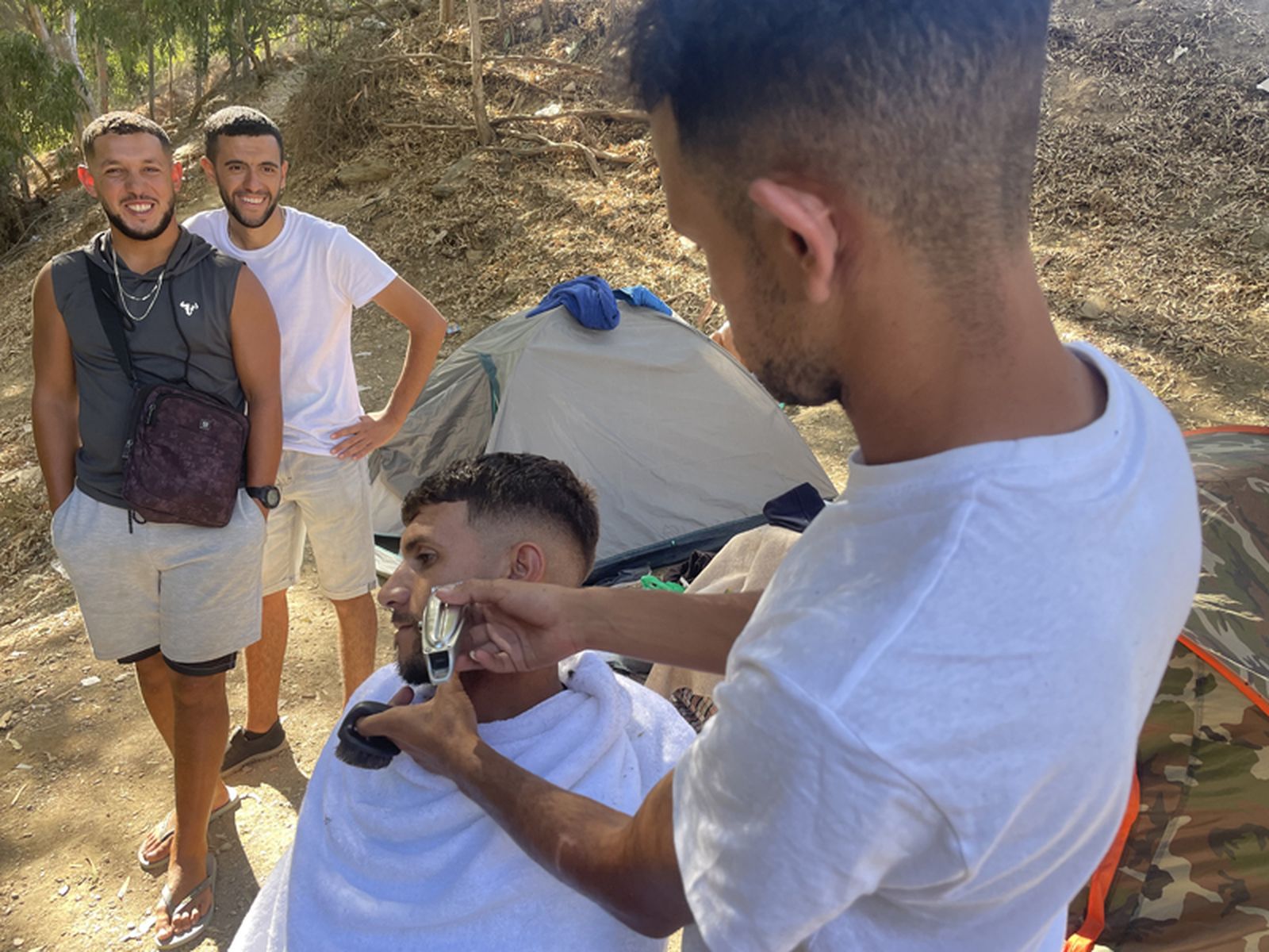 Isa, un barbero argelino, arregla a uno de los migrantes que acampa a las afueras del CETI. / FOTO REDUAN