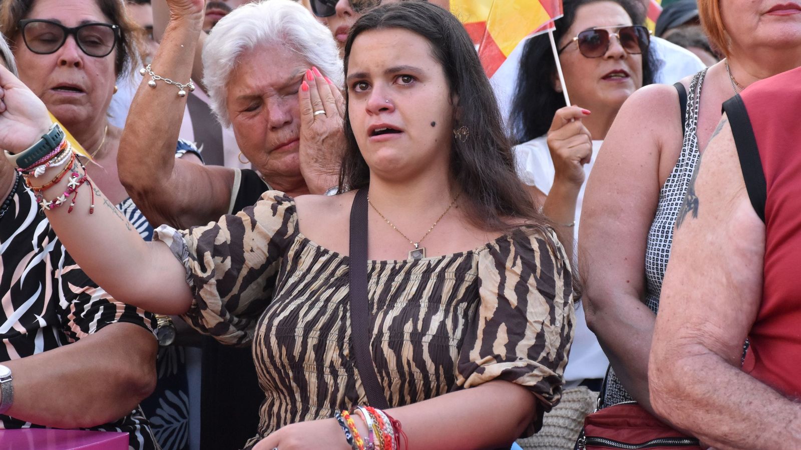 Varias mujeres, emocionadas mientras oyen y cantan el himno de Ceuta durante la concentración