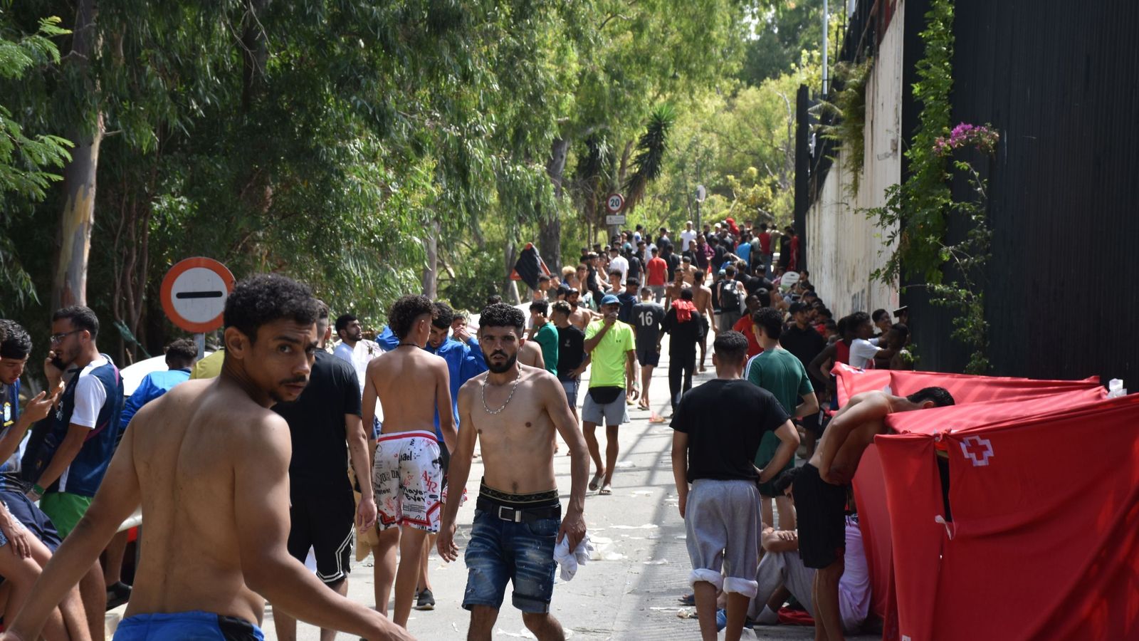 Migrantes en las inmediaciones del CETI a la espera de ingresar en las instalaciones, este jueves