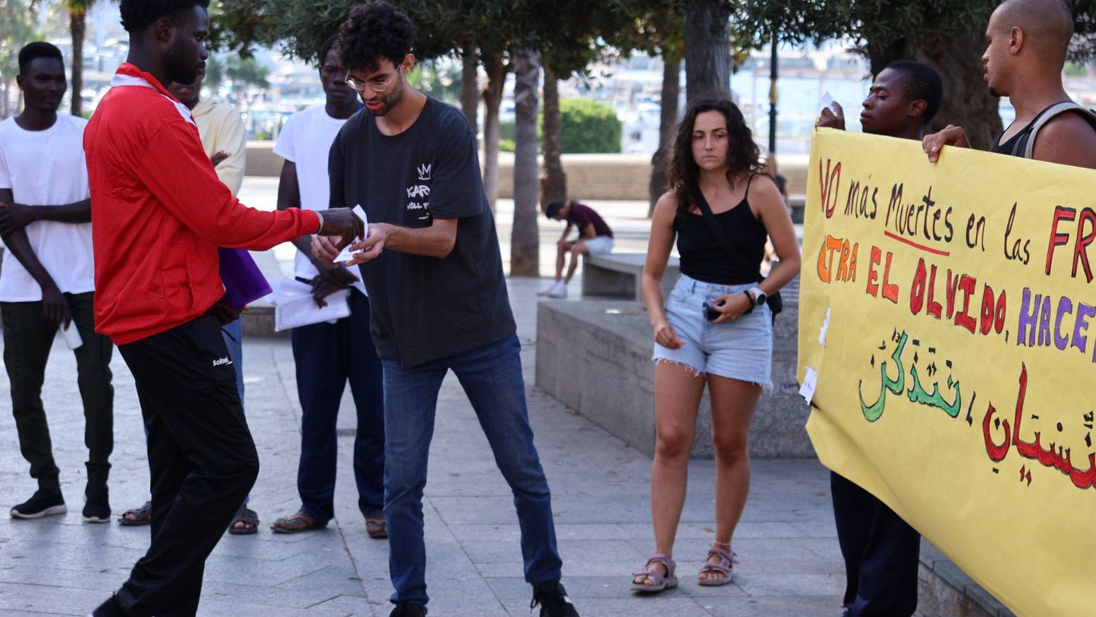 Una persona entregando a Ramsés un papel con el nombre de un fallecido para pegarlo en la pancarta