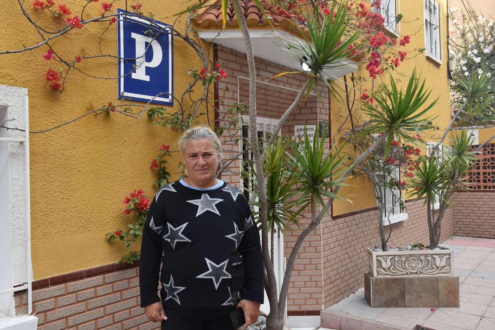 Mónica Raya posa a las puertas de la Pensión La Puntilla, donde pernocta desde el miércoles tras tres meses durmiendo en la playa de la Ribera