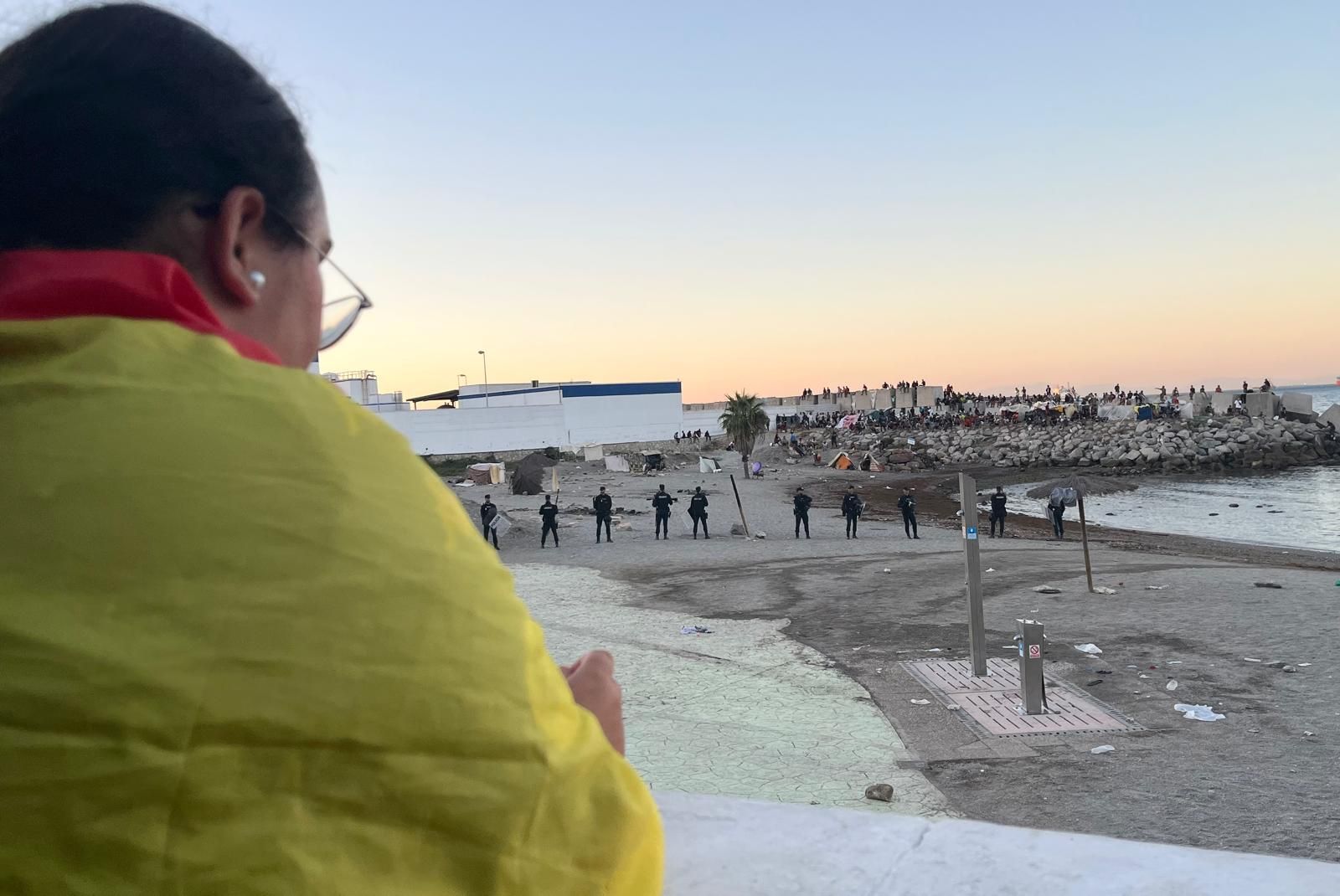 Una manifestante ceutí observa el cordón policial para proteger a los migrantes en Benítez
