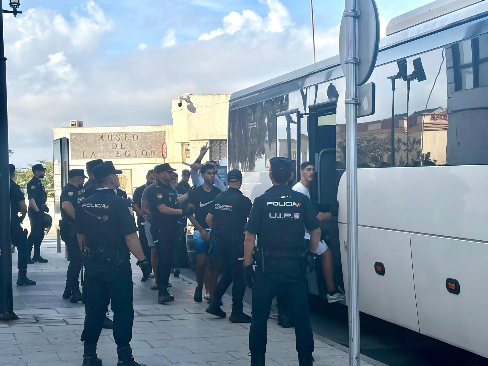 Migrantes argelinos salen de un furgón policial e ingresan en el autobús que los llevaría al Puerto.