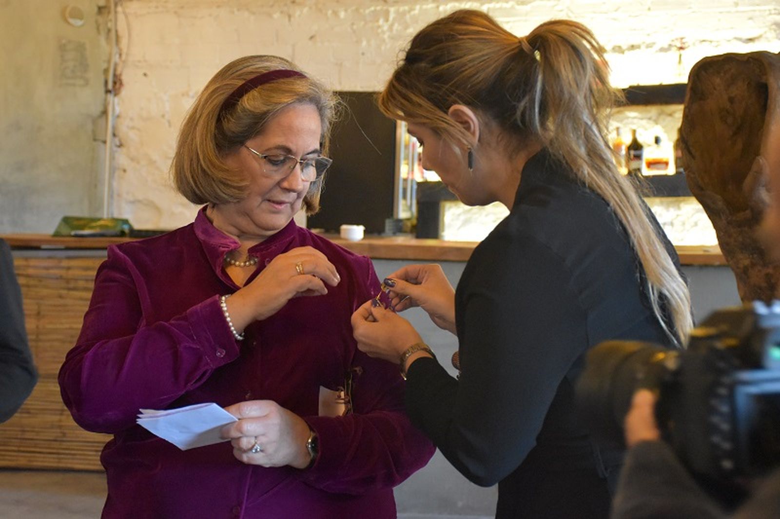 Nabila Benzina, consejera de Sanidad, ayudó a Carmen Recio Jaraba a colocarse su escudo de oro, máxima condecoración del Colegio de Farmacéuticos de Ceuta / FOTO G.S. Nabila Benzina, consejera de Sanidad, ayudó a Carmen Recio Jaraba a colocarse su escudo de oro, máxima condecoración del Colegio de Farmacéuticos de Ceuta / FOTO G.S.