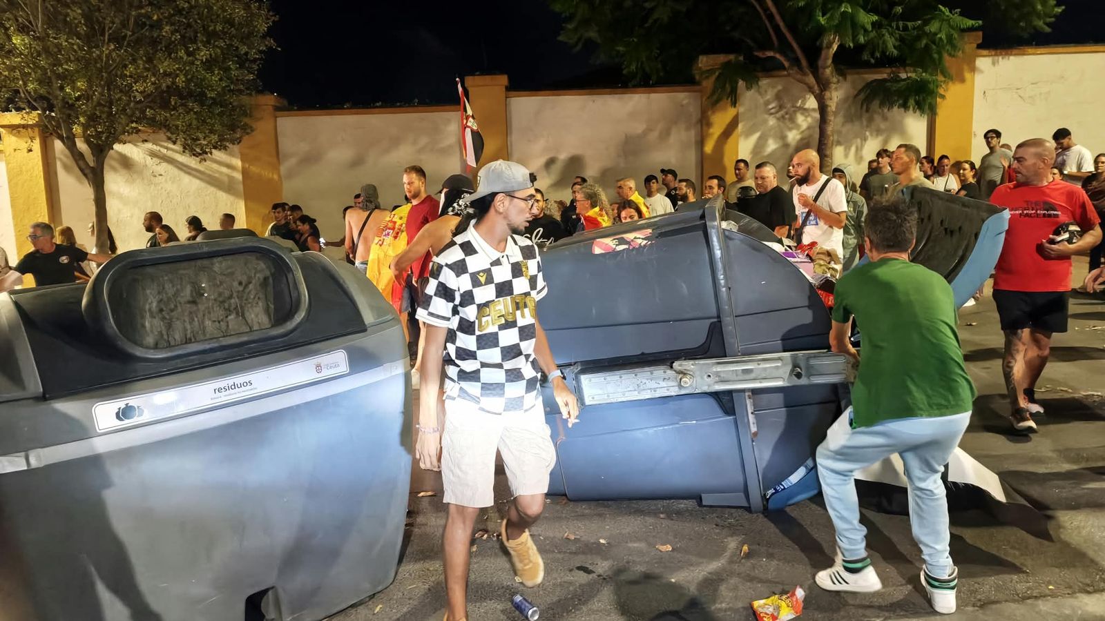 Ciudadanos se manifiestan en las barriadas de la ciudad contra la gestión de la crisis y tiran contenedores al suelo