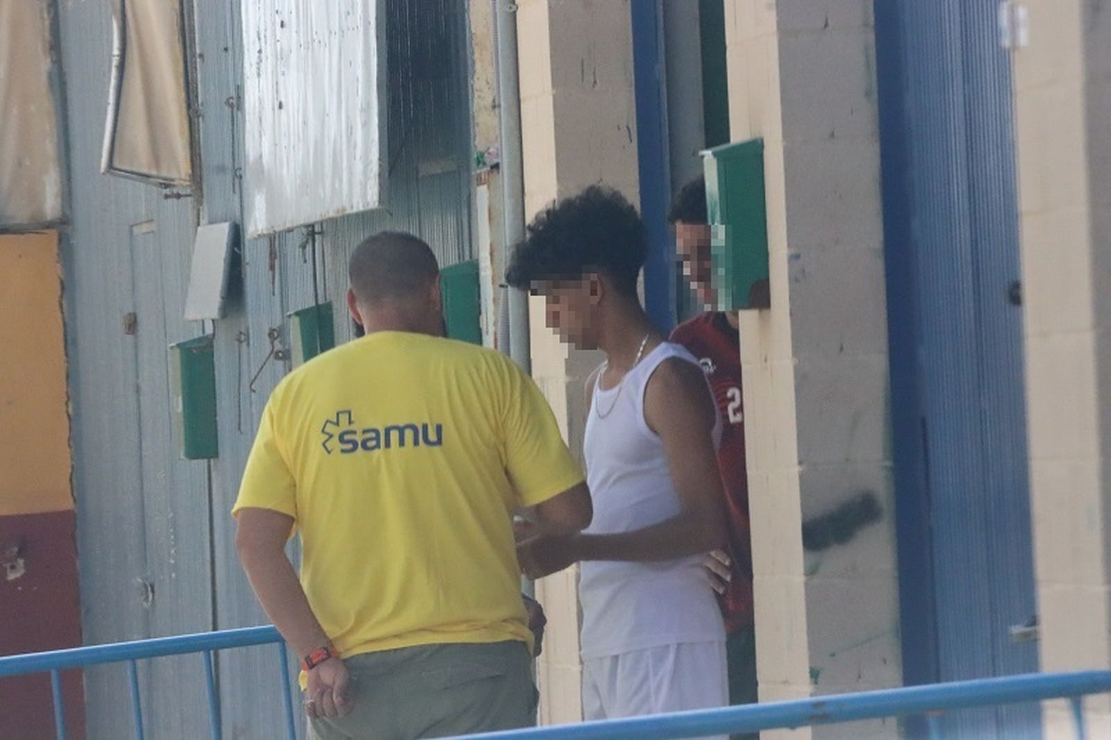 Un trabajador del SAMU conversa con dos chicos migrantes a las puertas del centro de acogida 'Nueva Esperanza'. / FOTO REDUAN