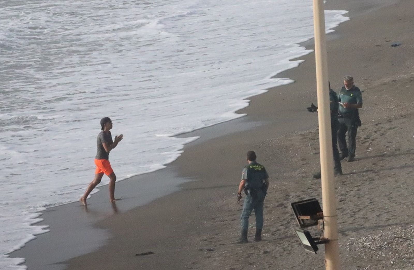 Un joven migrante llega este martes a la playa del Tarajal, donde le esperan varios agentes de la Guardia Civil. / FOTO REDUAN