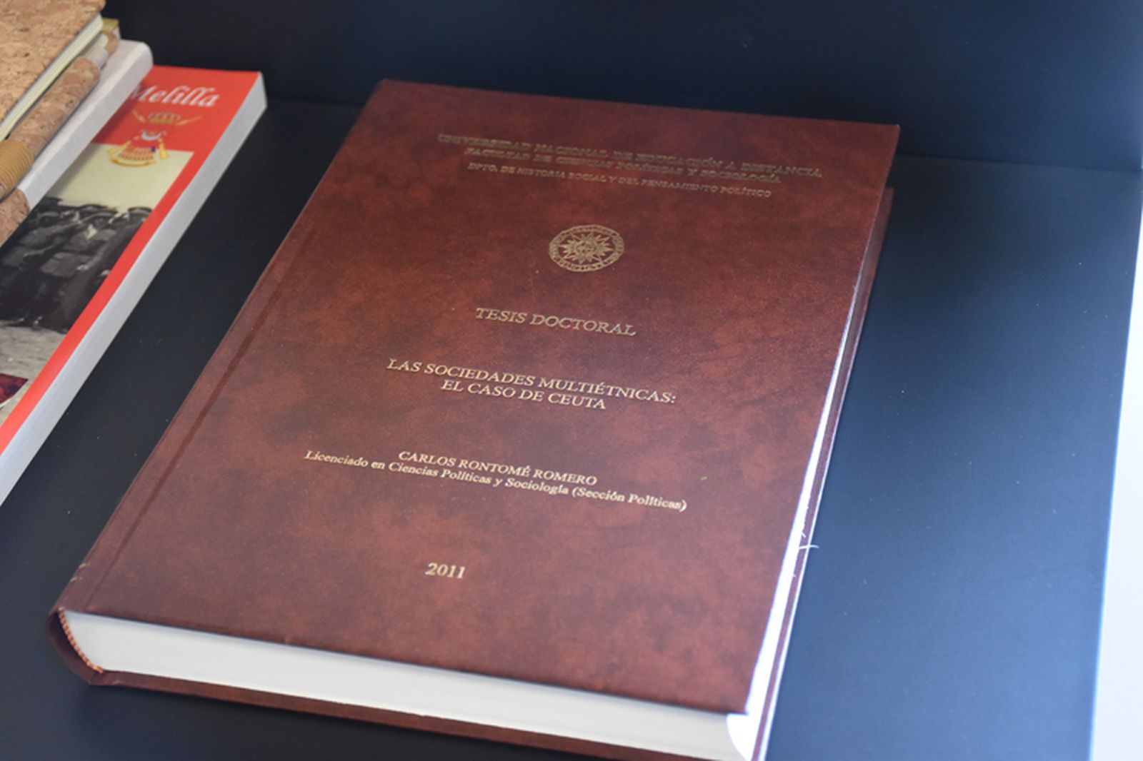 Ejemplar de la tesis doctoral defendida por Carlos Rontomé en 2011. 'Las sociedades multiétnicas: el caso de Ceuta' obtuvo un sobresaliente 'Cum laude'. / FOTO G.S.
