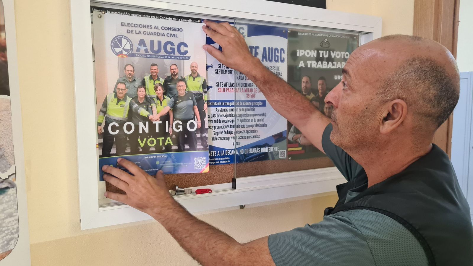 Un guardia civil poniendo el cartel de las elecciones.