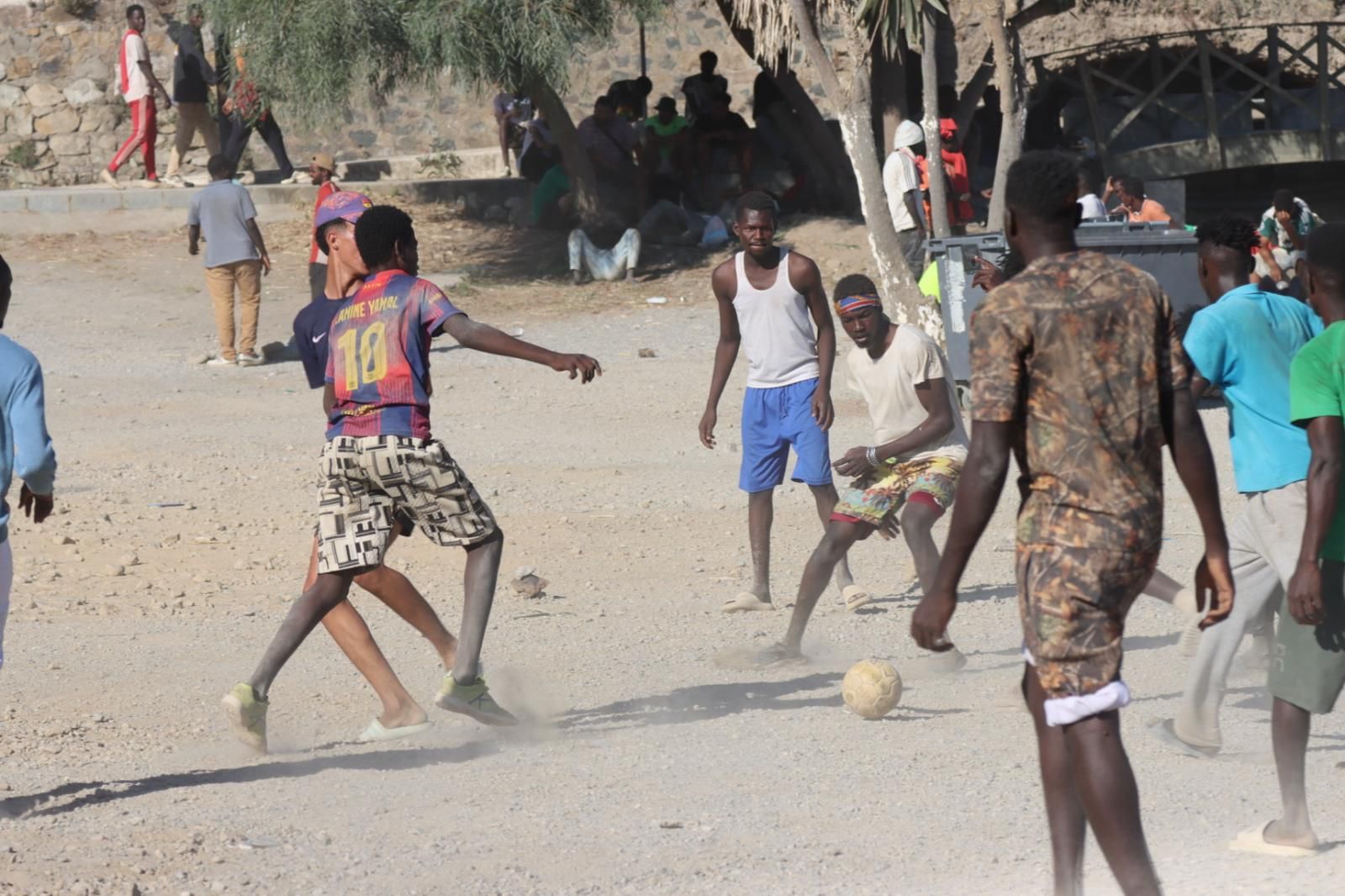 Migrantes jugando al fútbol en la playa a la espera de resolver su futuro