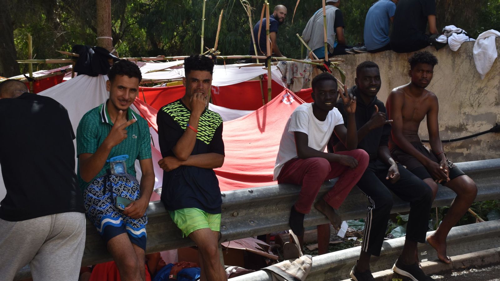 Migrantes en las inmediaciones del CETI a la espera de ingresar en las instalaciones, este jueves