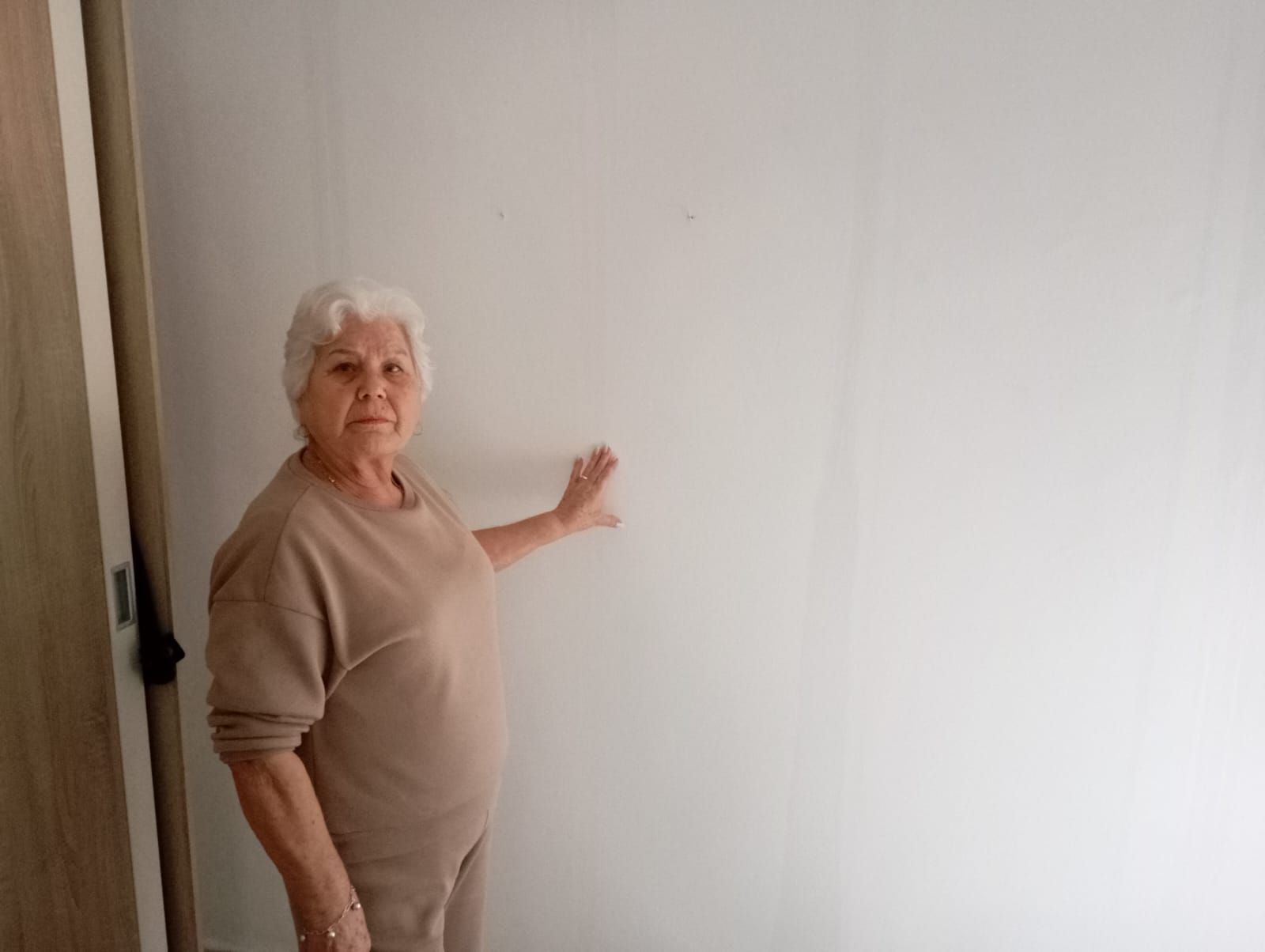 Encarnación toca la pared de su casa