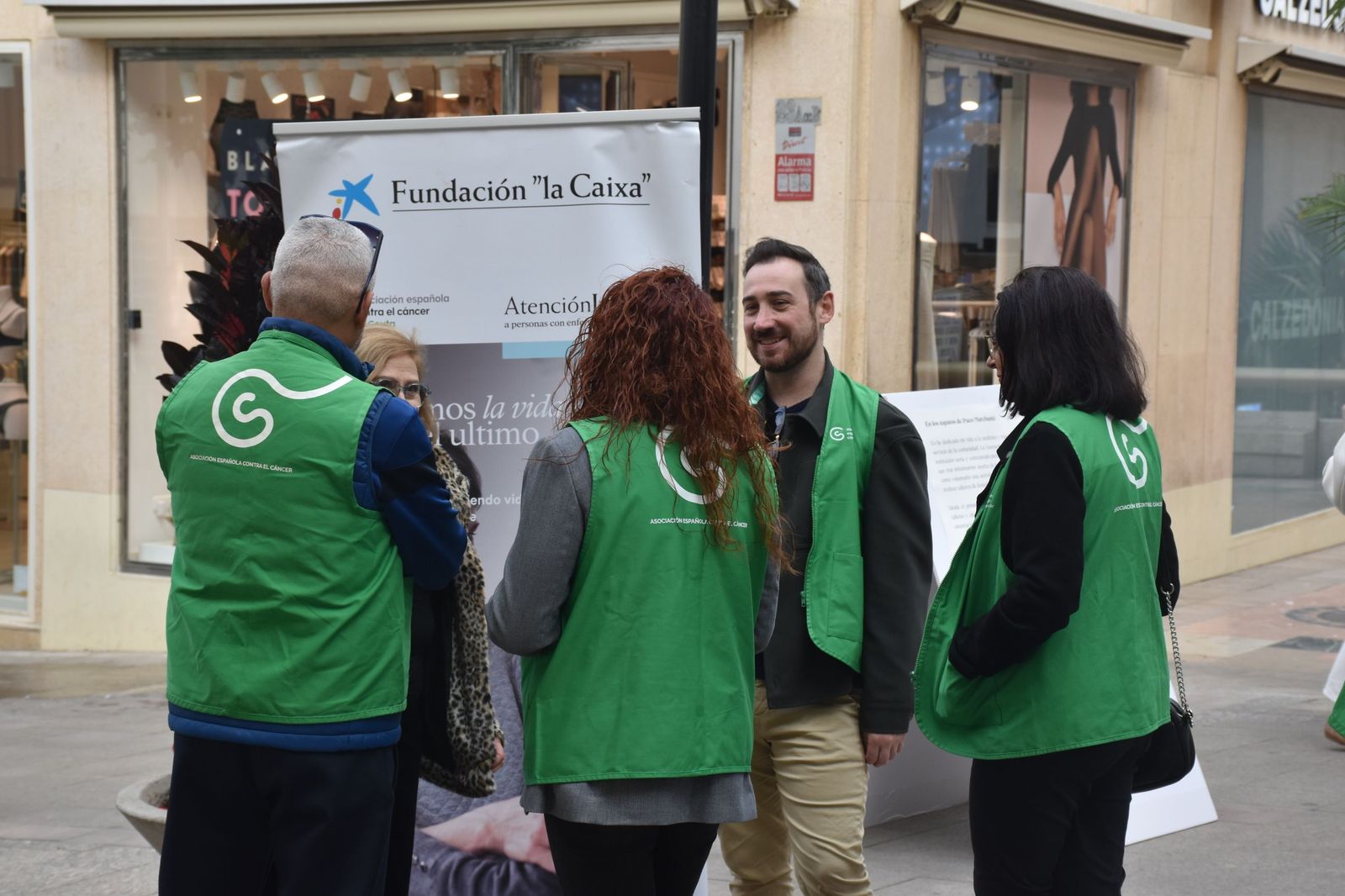Miembros de la AECC conversan junto a la muestra 'En sus zapatos', celebrada el pasado año