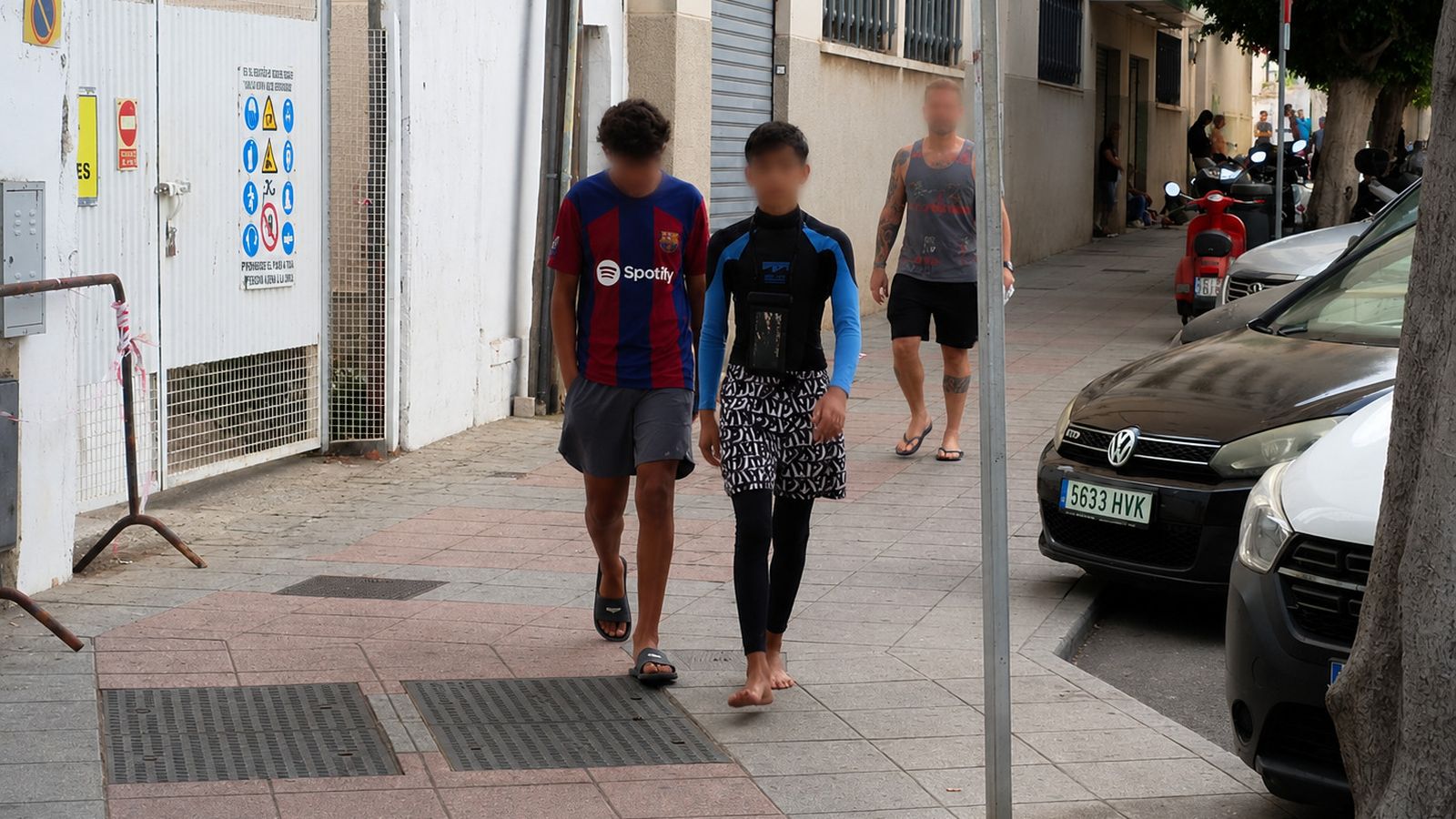 Dos chavales, uno con la camiseta del Barça y otro con traje de neopreno, dejan el Paseo de Colón