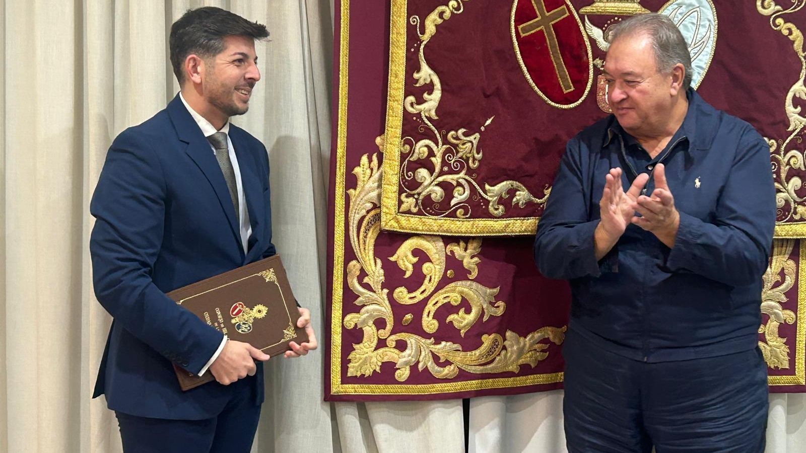 Adán del Campo recibe las guardas para el pregón de la Semana Santa 2026 de manos del presidente del Consejo de Hermandades, Jesús Bollit