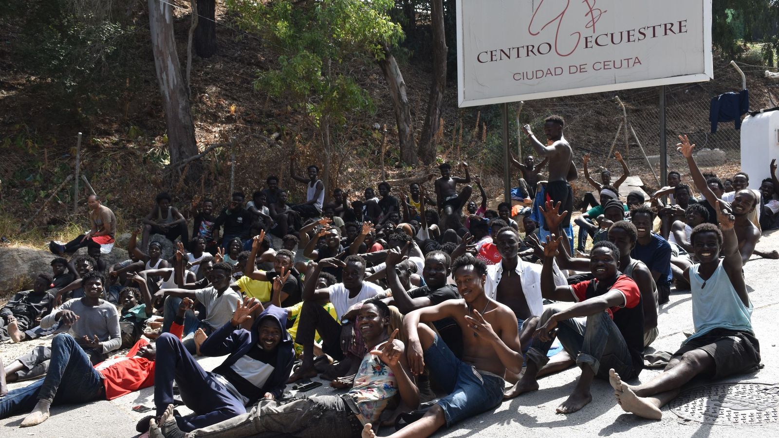 Migrantes en las inmediaciones del CETI a la espera de ingresar en las instalaciones, este jueves