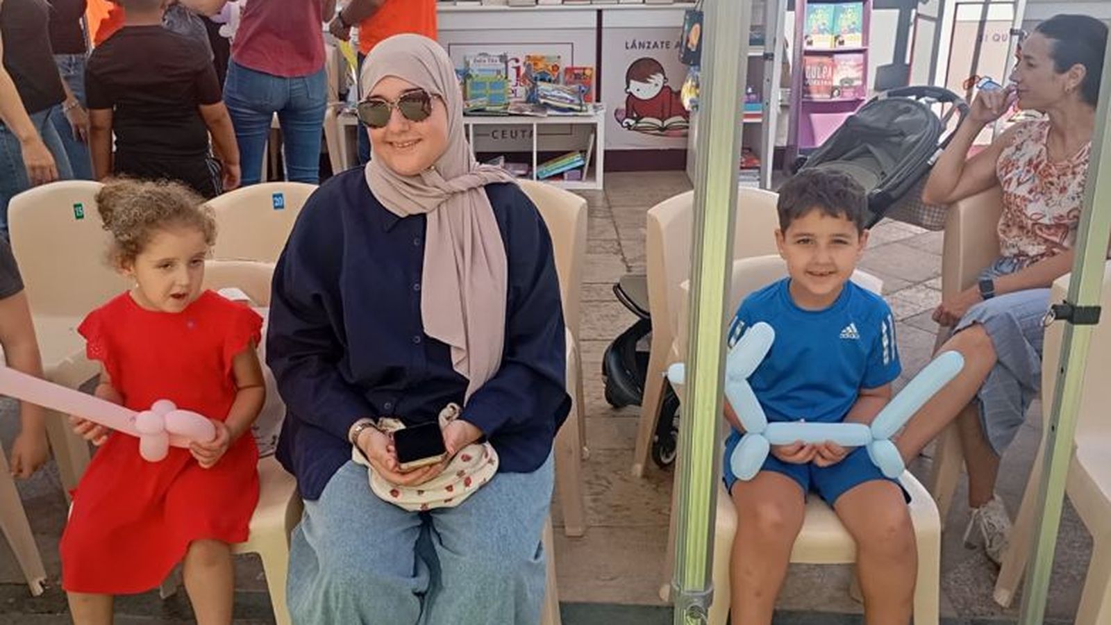 Una madre y sus dos hijos esperan, pacientemente, a que comience el espectáculo de títeres