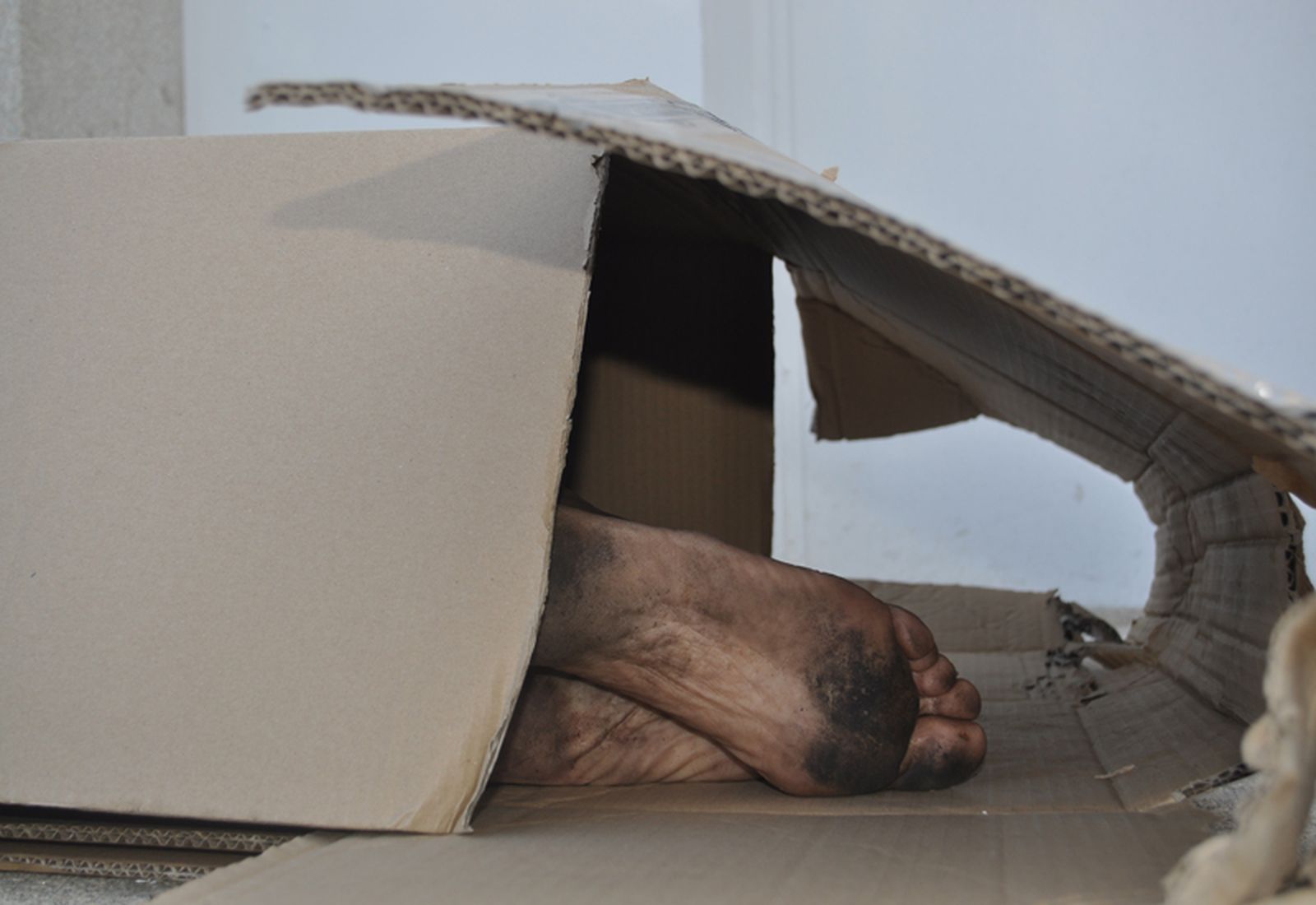 Un indigente duerme en la calle protegido por unas cajas de cartón