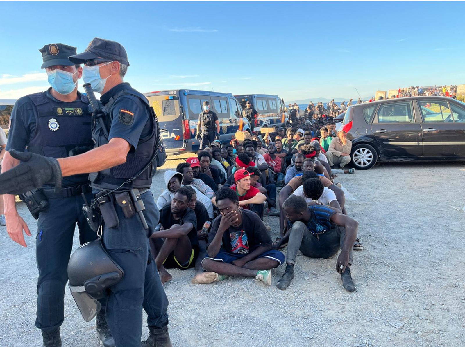 Policías custodian a un grupo de migrantes junto a la playa de El Trampolín