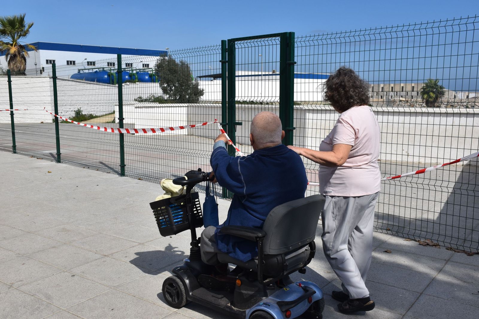 Myriam y Ricardo pasean frente a su casa, en Benítez, y observan el vallado instalado para evitar el acceso a la Desalinizadora