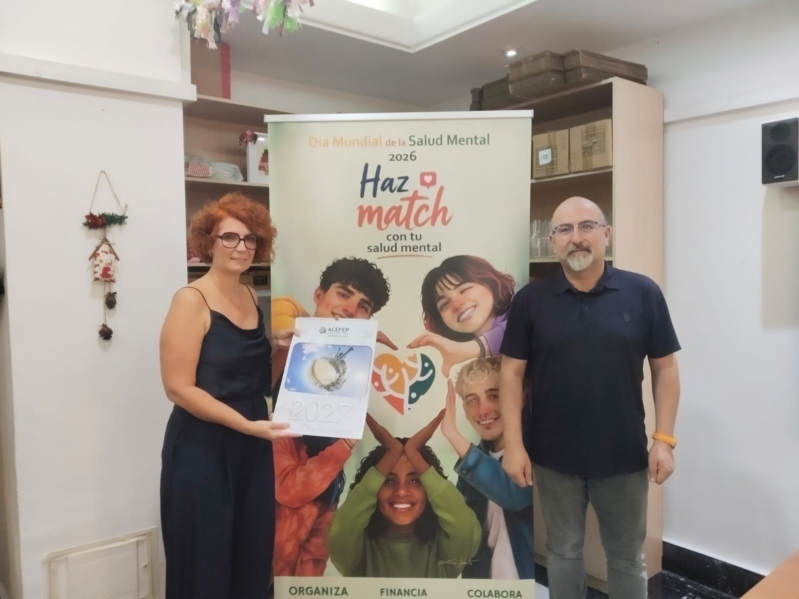 Los directivos de la asociación posan junto al póster anunciador del Día Internacional