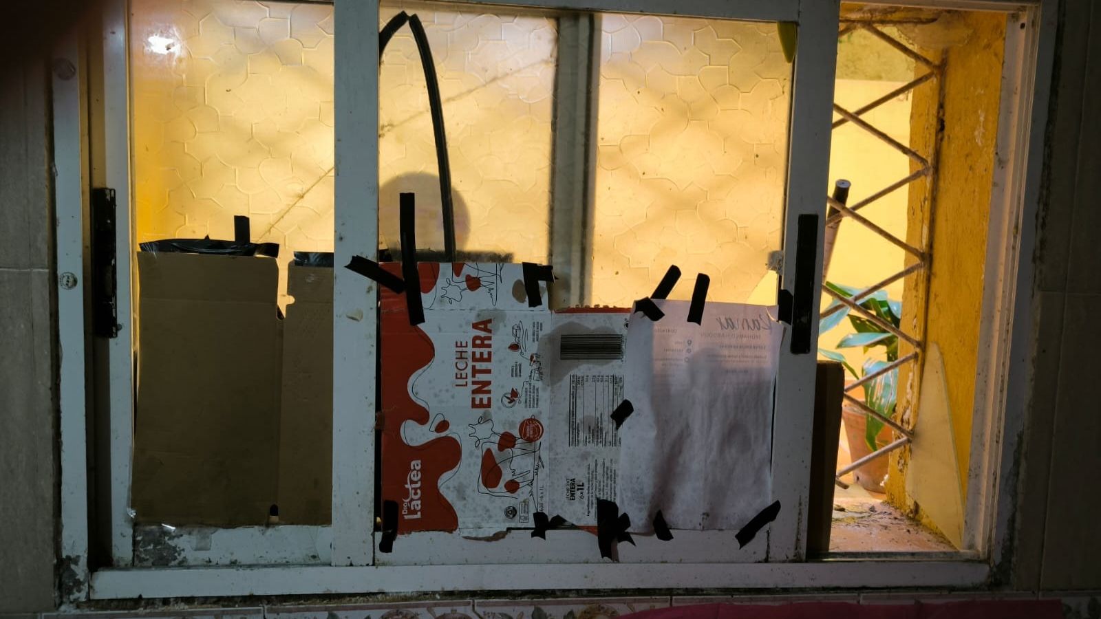 Una ventana, tapiada con cartones de leche.