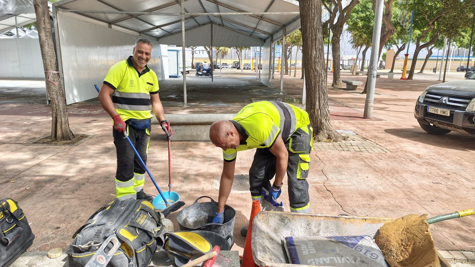Dos albañiles terminando de rellenar un hueco en el suelo del parque