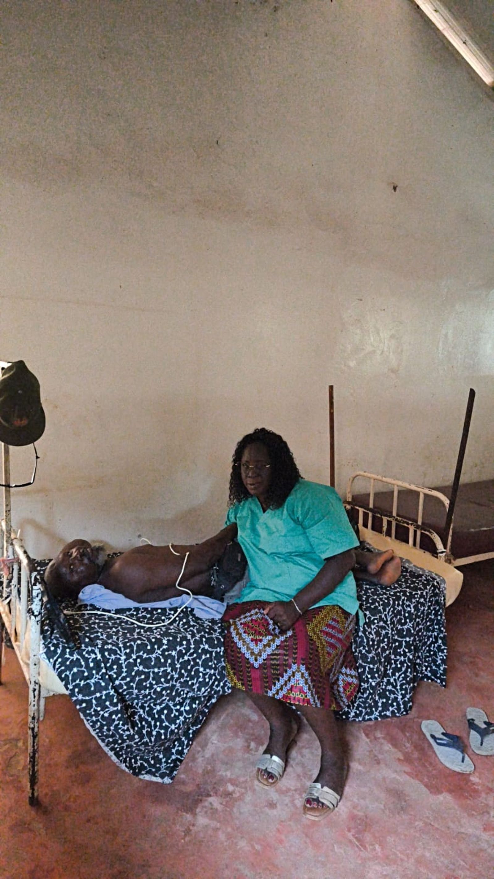 Una mujer acompañando a un hombre al que se le está realizando un tratamiento en Guinea Bissau