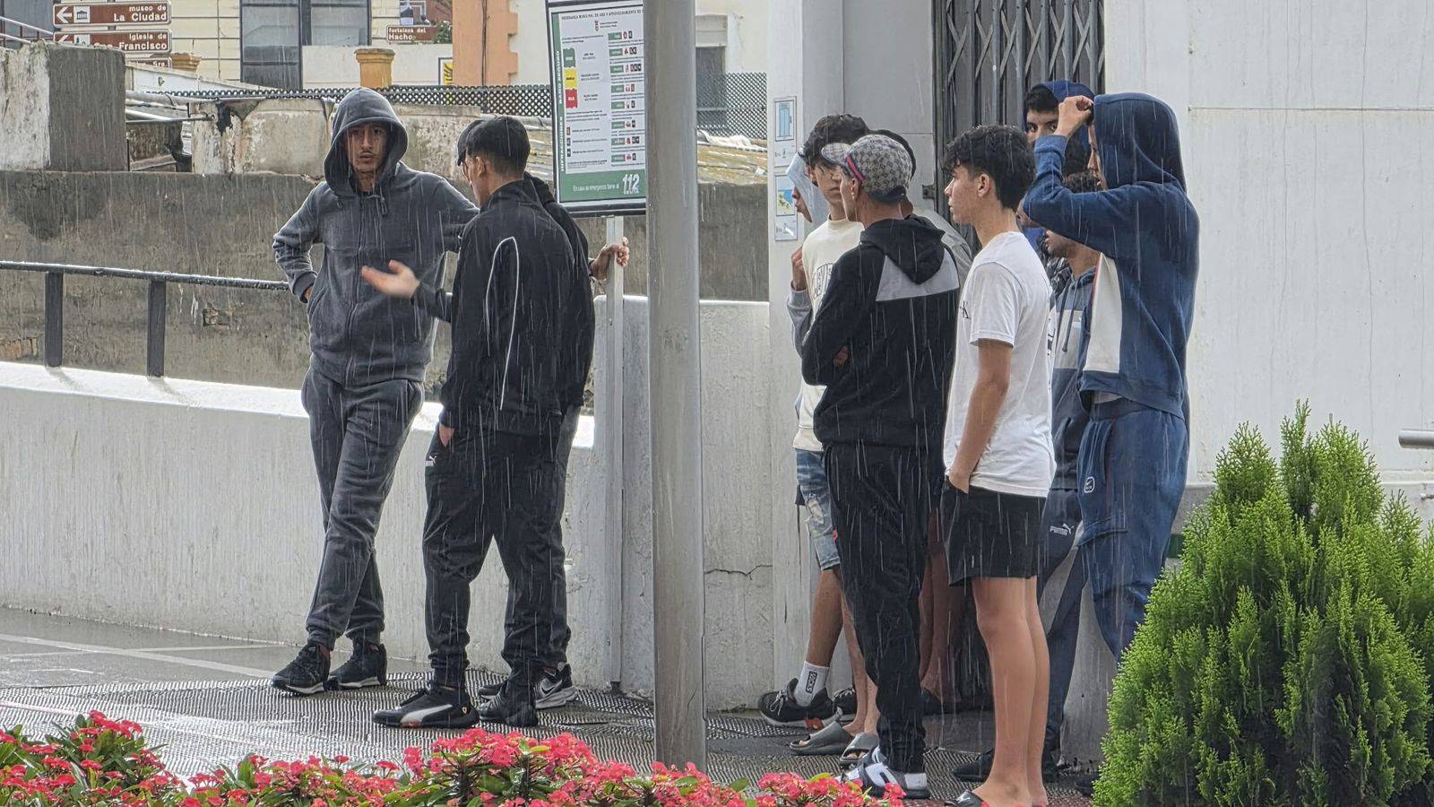 Menores migrantes esperan bajo la lluvia para ser filiados tras ser desalojados de asentamientos ilegales