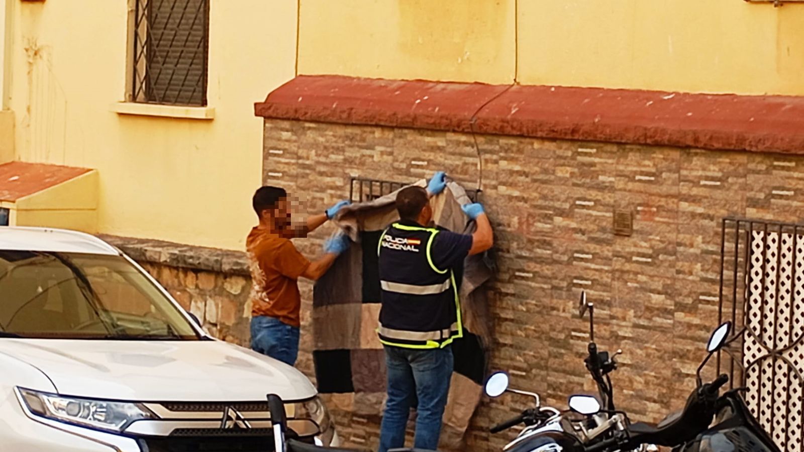 La Policía Nacional tapa una de las ventanas de la vivienda donde se ha producido el fatídico fallecimiento de un bebé de 9 días y donde se detuvieron a sus progenitores y a un tio del pequeño