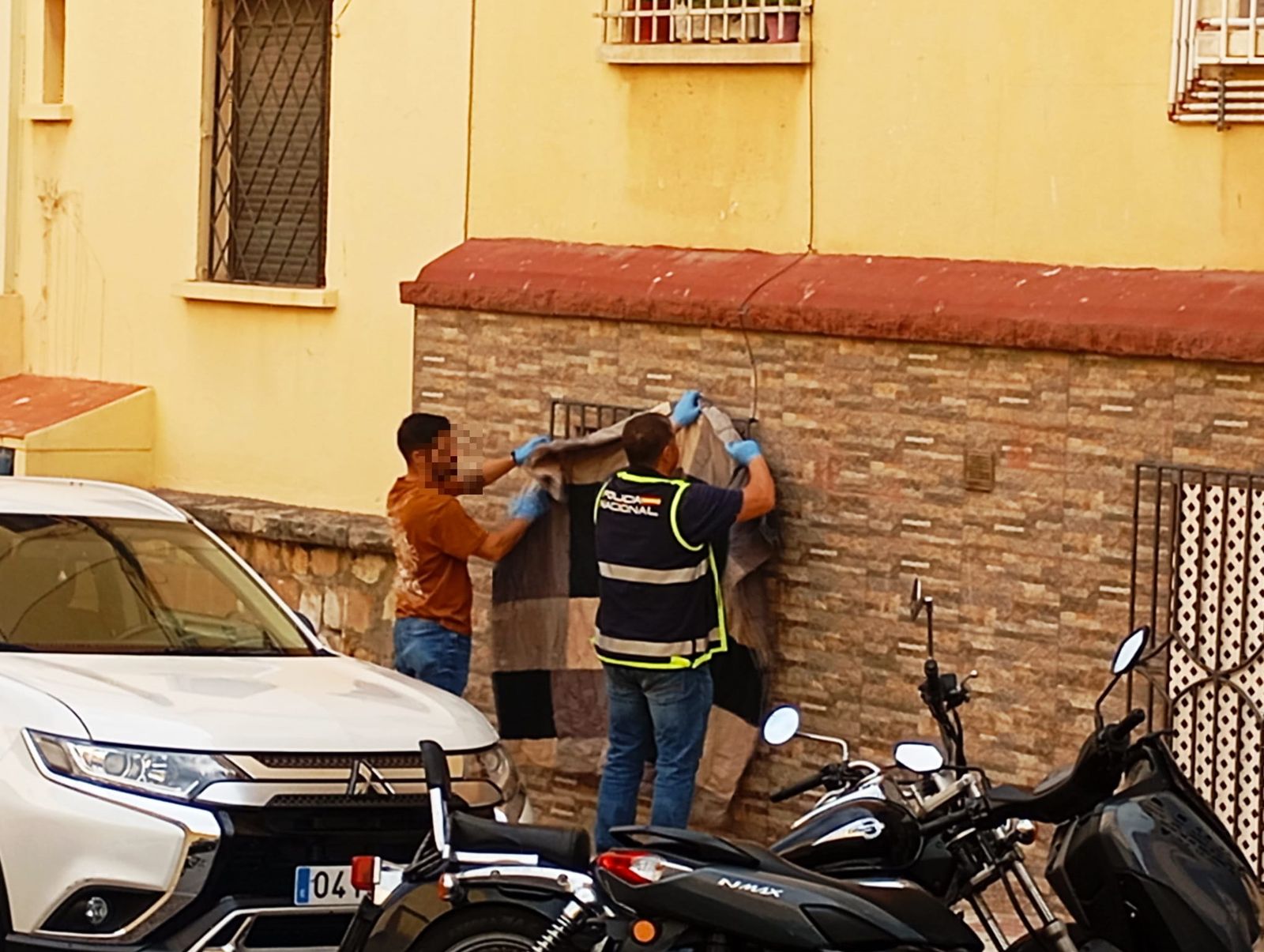 La Policía Nacional tapa una de las ventanas de la vivienda donde se ha producido el fatídico fallecimiento de un bebé de 9 días y donde se detuvieron a sus progenitores y a un tio del pequeño