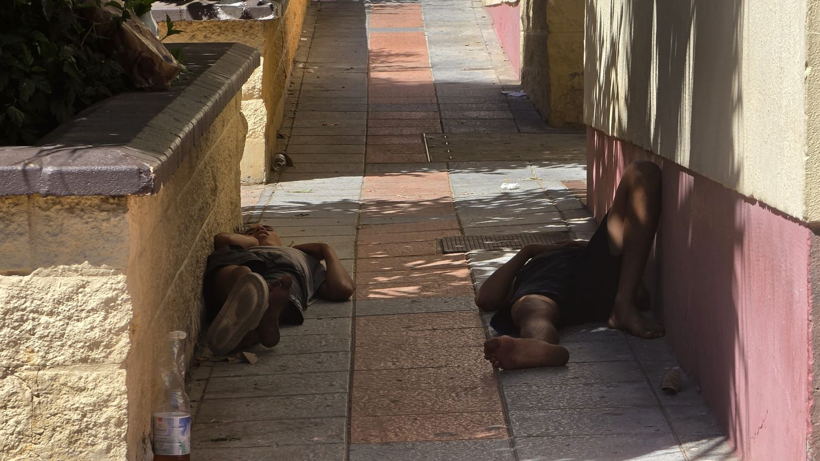 Dos migrantes descansando en una acera del Polígono Virgen de África